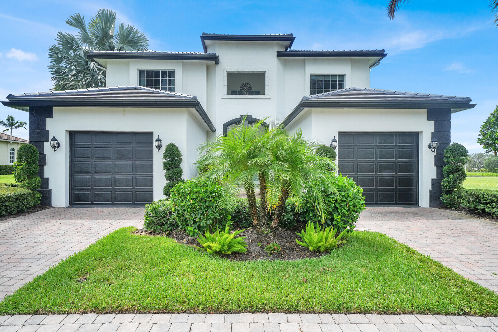 Contemporary stucco exterior featuring a tiled roof and dual garage doors