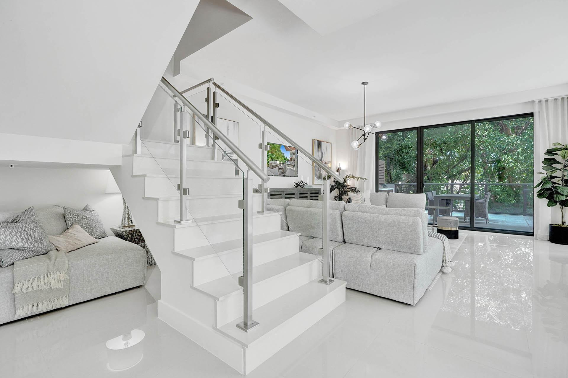 Contemporary interior featuring a prominent staircase with glass and stainless steel railing
