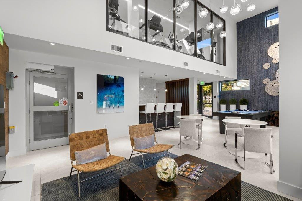 Modern open-concept living space featuring soaring ceilings with skylights, polished concrete flooring, and a dramatic mezzanine level with glass railings