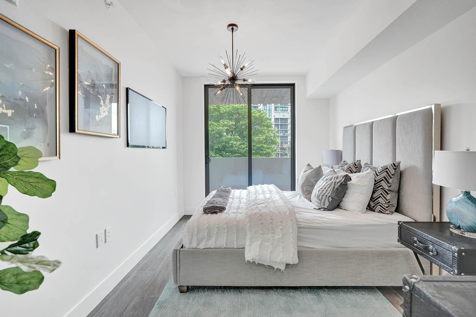 Spacious room featuring wood-finish flooring, a contemporary sputnik chandelier, and a large sliding glass door opening to a private balcony