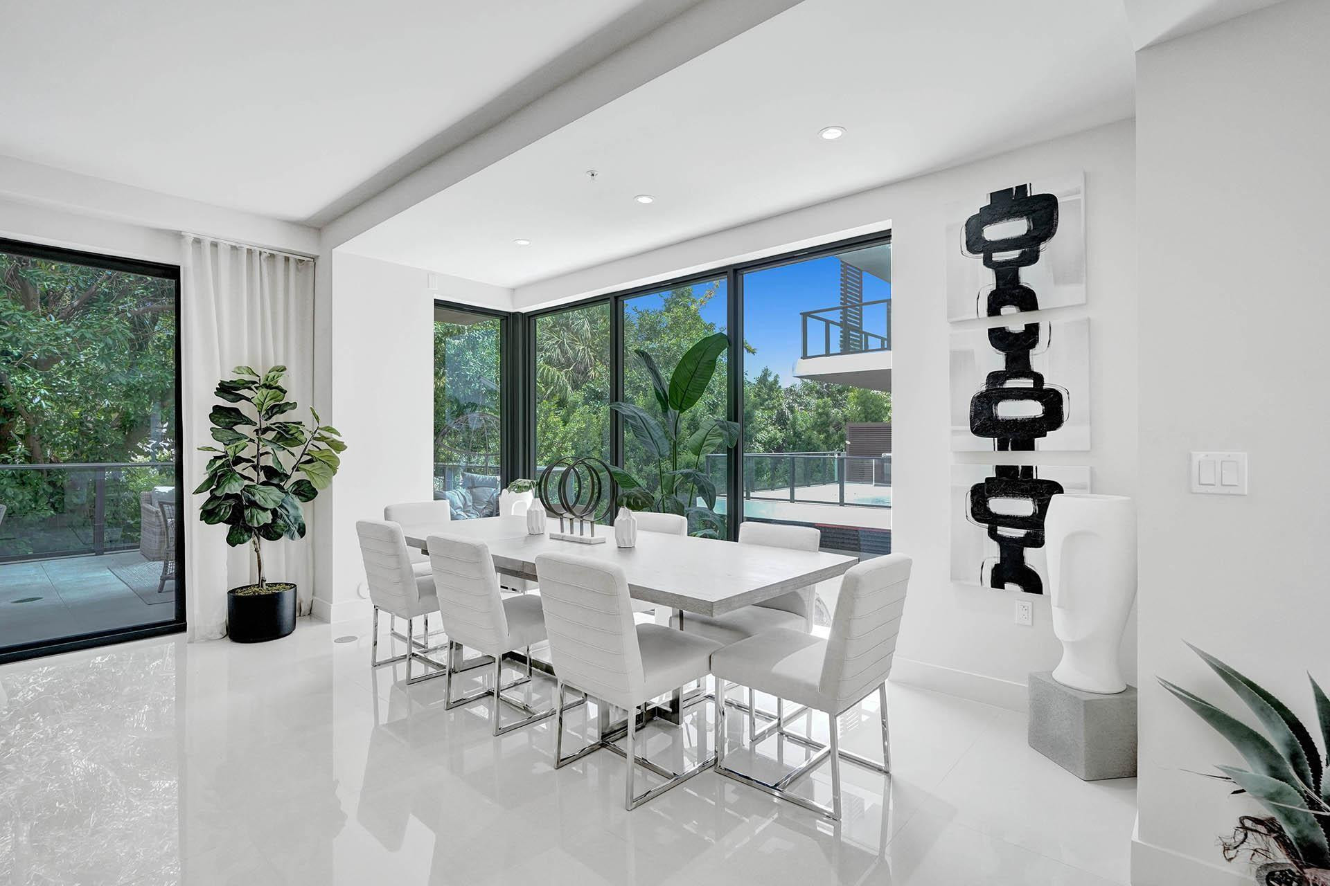 Spacious interior featuring pristine white flooring, an expansive window wall, and a large sliding glass door opening to an outdoor patio