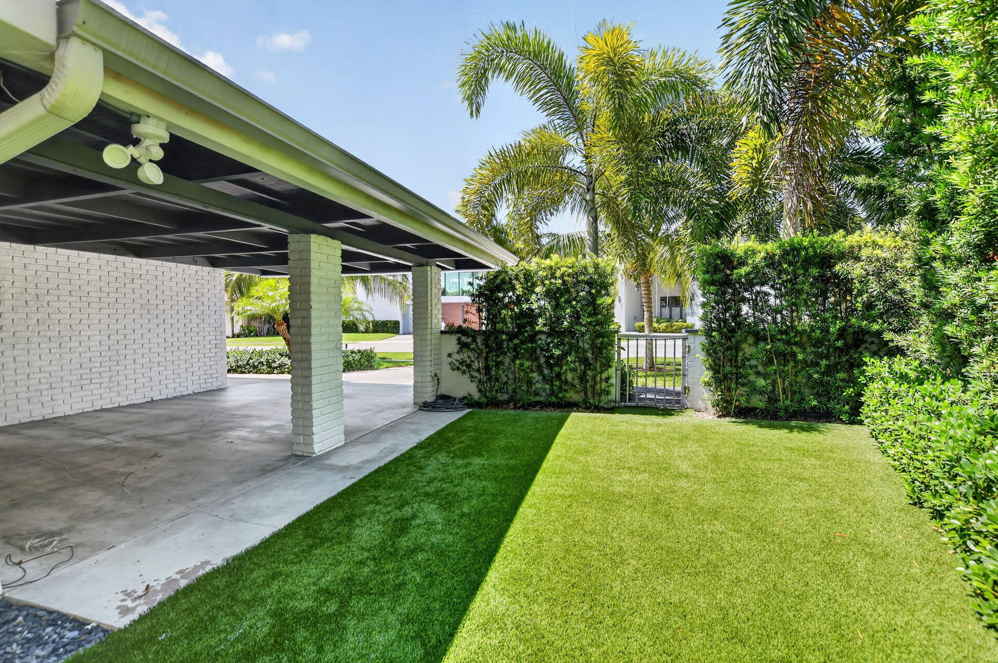 This is the West side elevation of the Carport, the yard is partially fenced in . The side and rear yards have recently installed artificial turf, no need for a mower, sprinklers, or fertilizer! Safe for children and pets too!