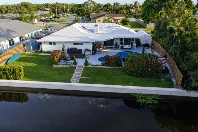 A stunning aerial view showcases this waterfront property with a spacious backyard, private pool, covered patio, and direct frontage along the navigable canal. Its beautiful landscaped with a concrete seawall completing this waterfront retreat!