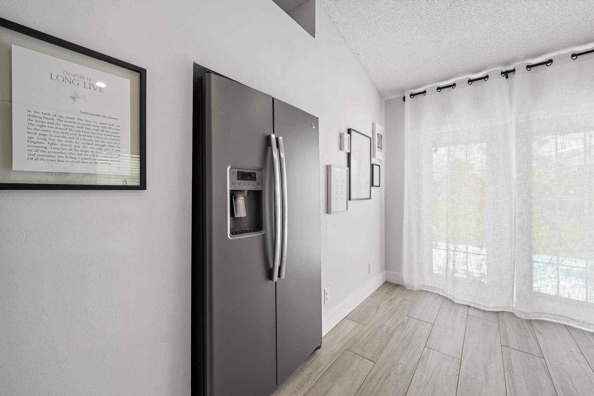 Stainless steel side-by-side refrigerator, vaulted ceiling, wood-finish flooring, and French doors