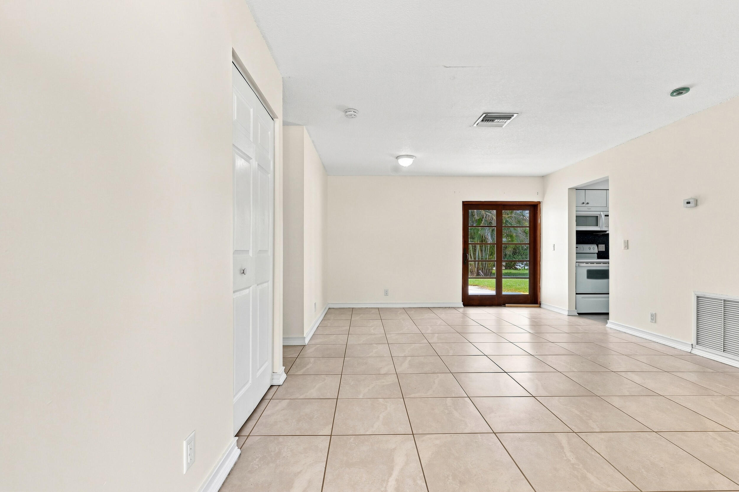 Bright tiled living area with recessed lighting and views toward the rear of the home.