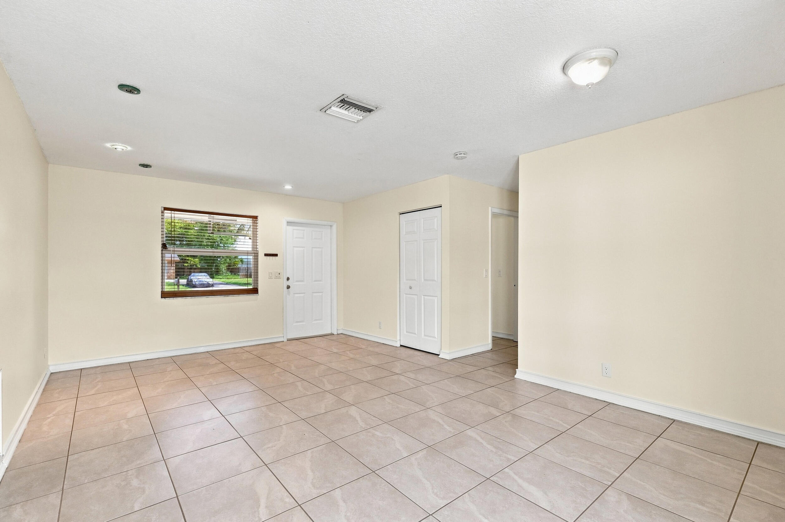 Spacious tiled interior with neutral walls and multiple windows for natural light.