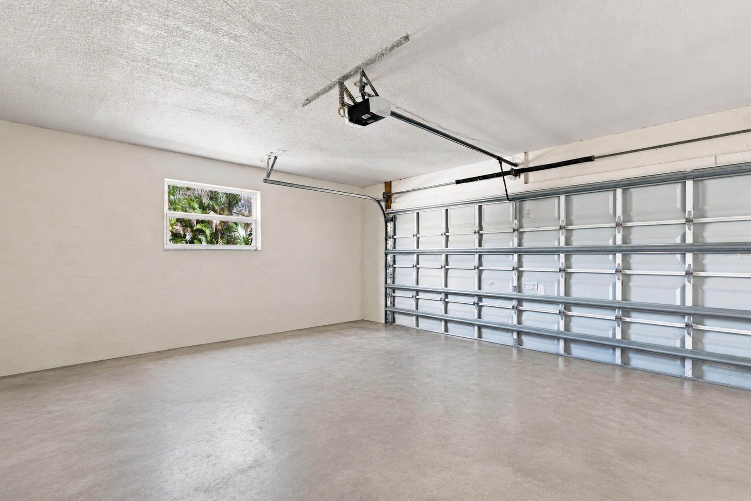 Attached garage with finished walls, overhead garage door, and additional storage space.