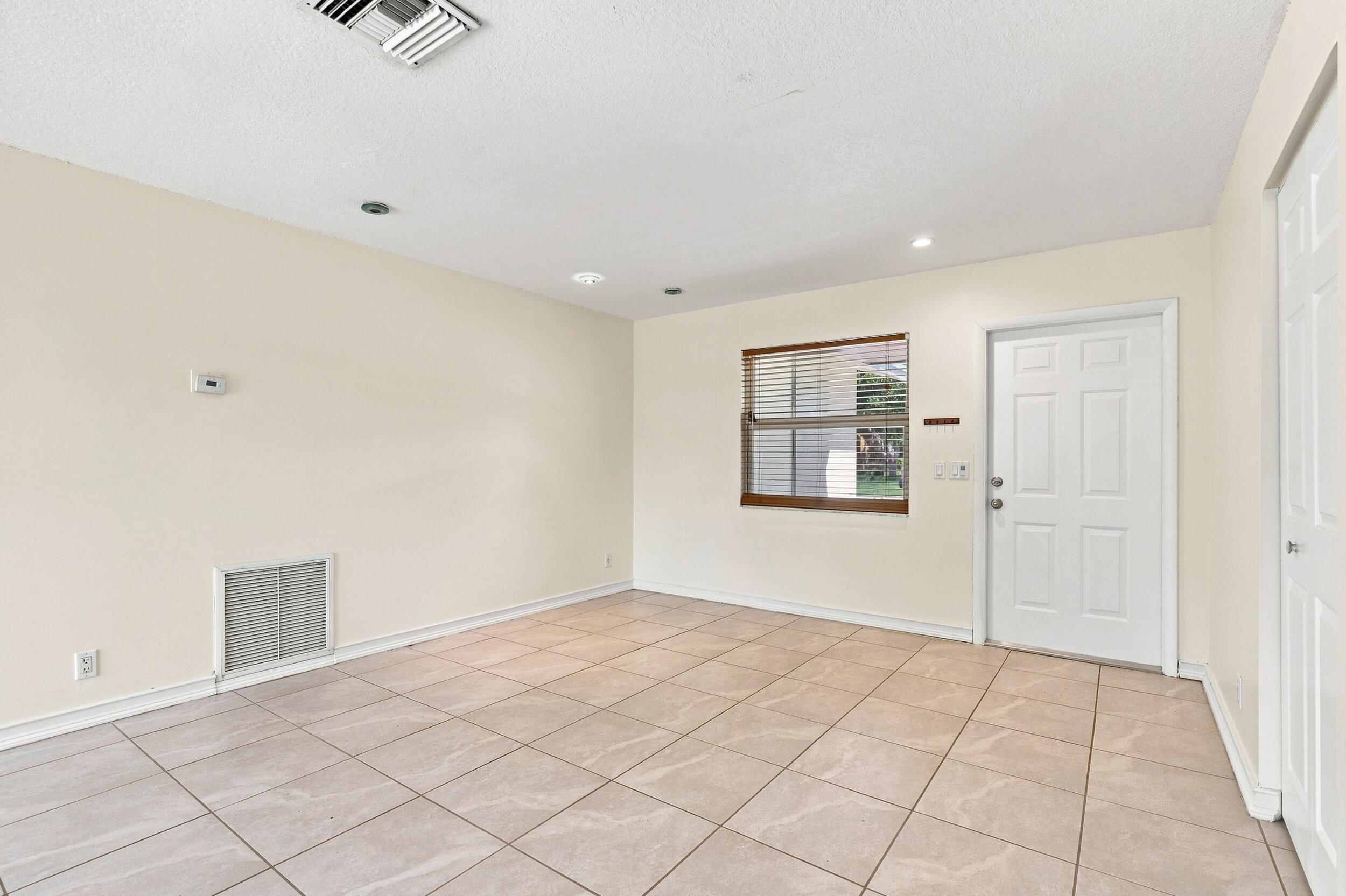 Tiled living space with neutral finishes, recessed lighting, and natural light.