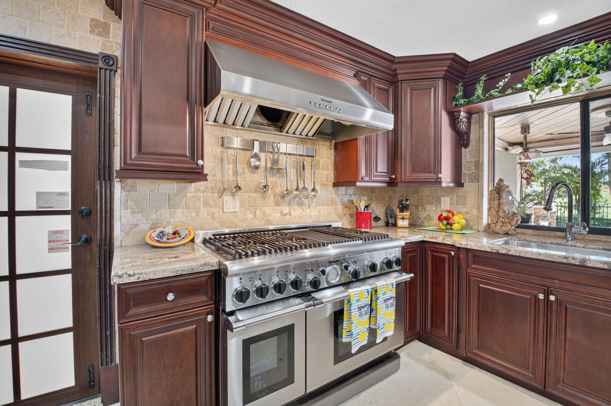 Professional Thermador GAS range with a grill and exhaust fan to the outside. Impact French door to the paver patio.
