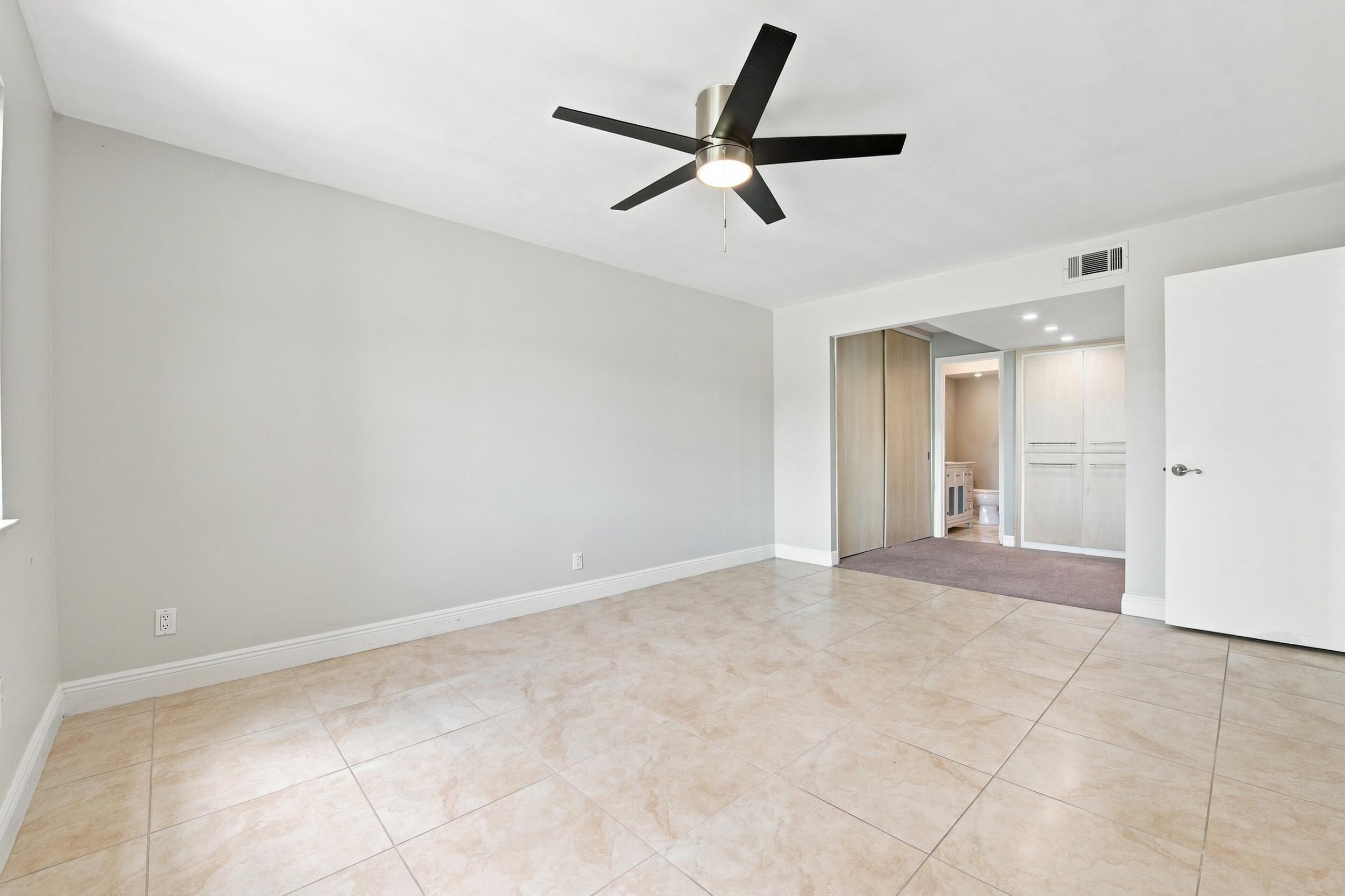 Spacious room featuring vaulted ceilings, a ceiling fan with integrated lighting, and light-toned tile flooring