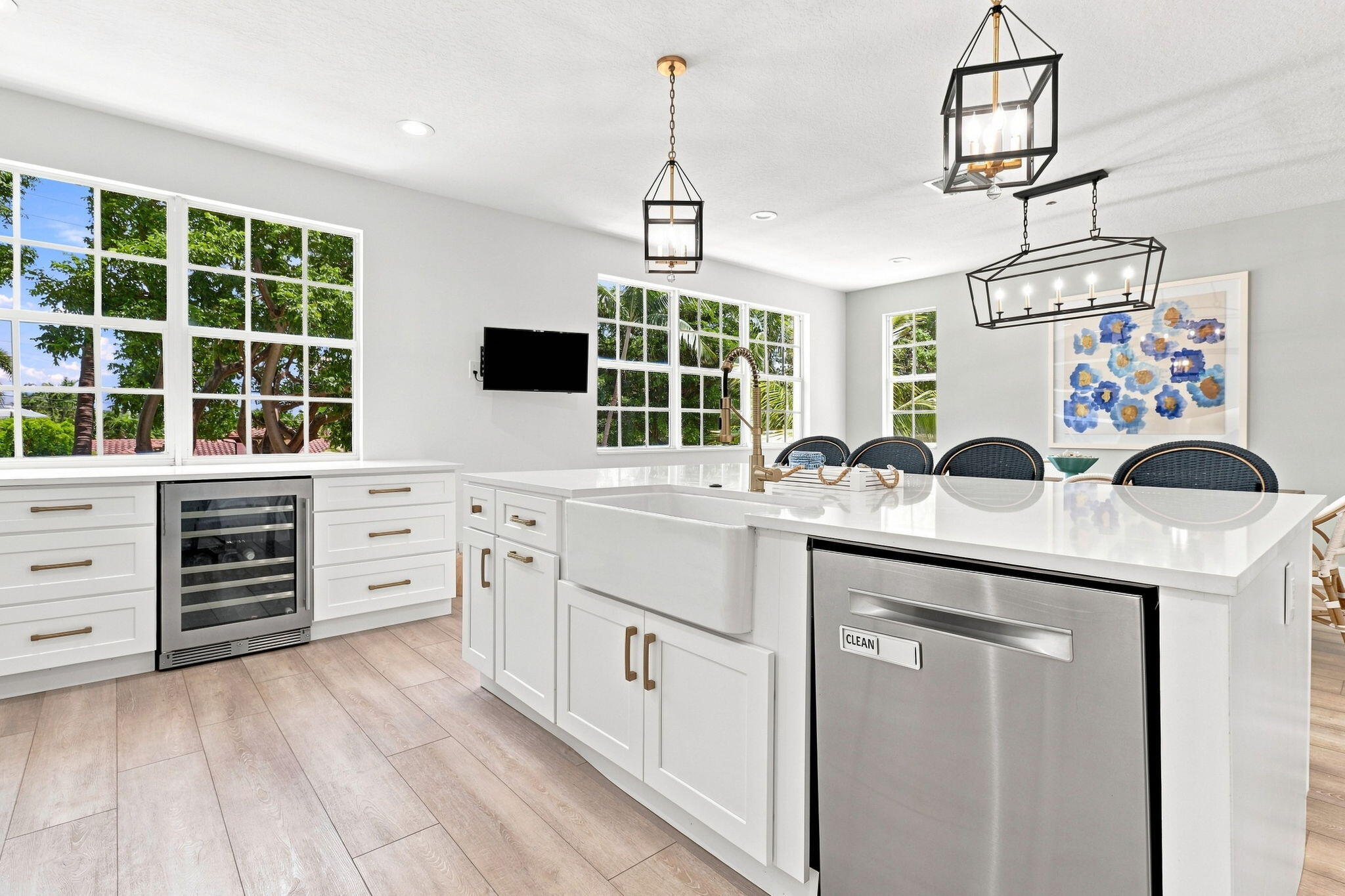 Kitchen featuring white cabinetry, light-toned luxury vinyl flooring, a white farmhouse sink, stainless steel dishwasher and built-in beverage refrigerator