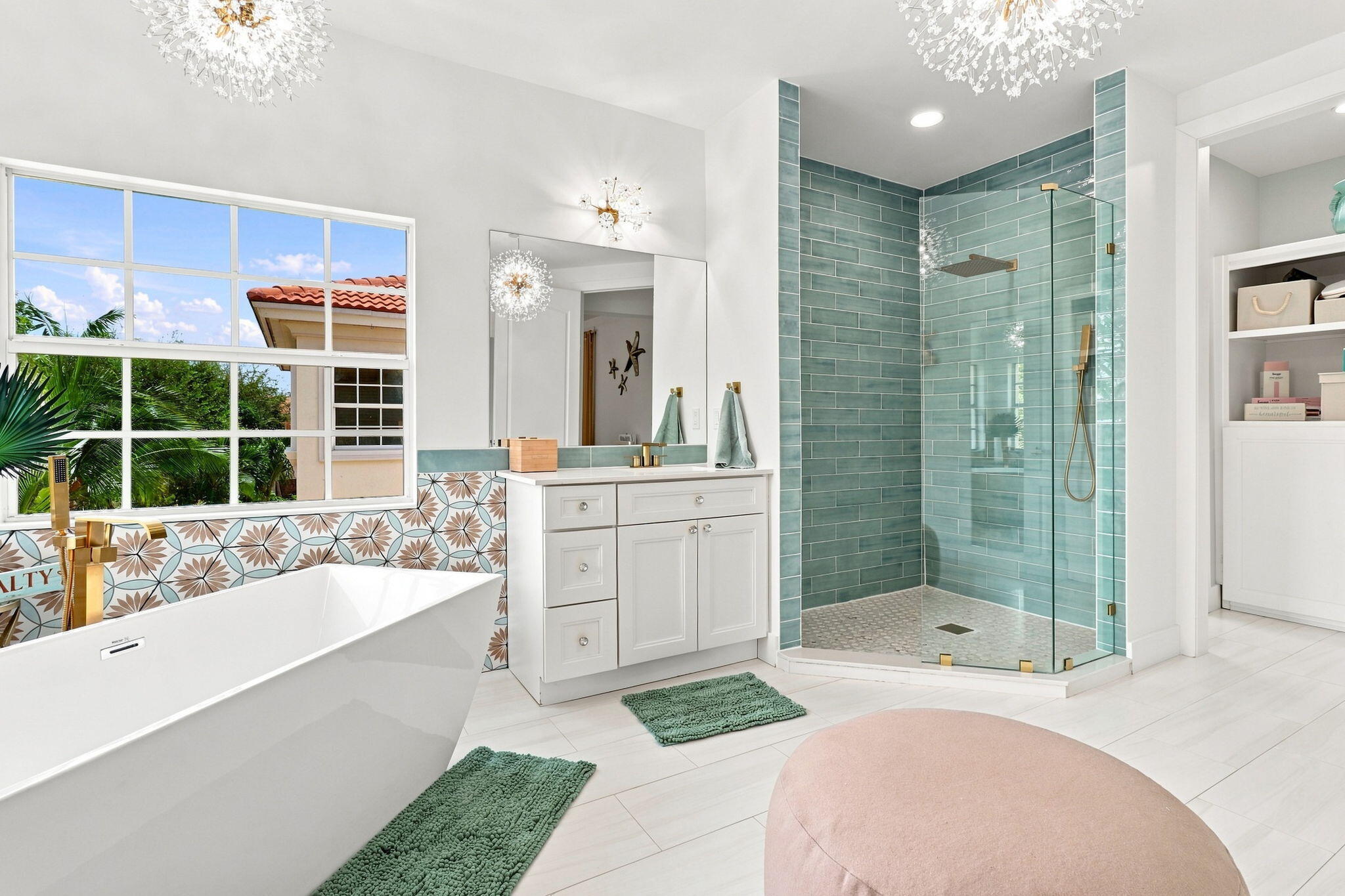 Freestanding soaking tub with floor-mounted faucet, glass-enclosed shower with subway tile surround, single vanity with integrated sink and built-in shelving