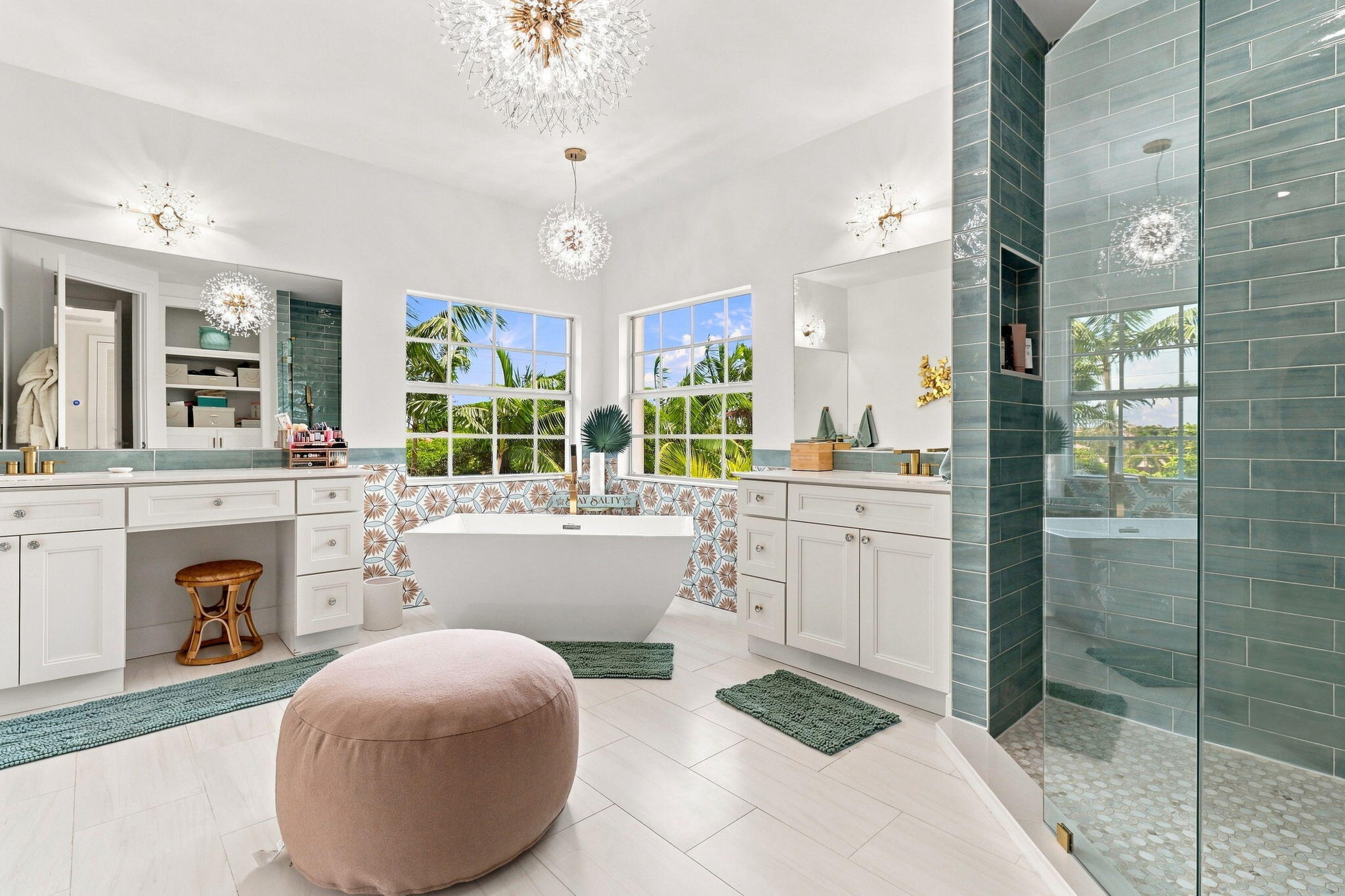 Freestanding soaking tub, dual vanity with white cabinetry, glass-enclosed shower with subway tile, white tiled flooring and multiple windows
