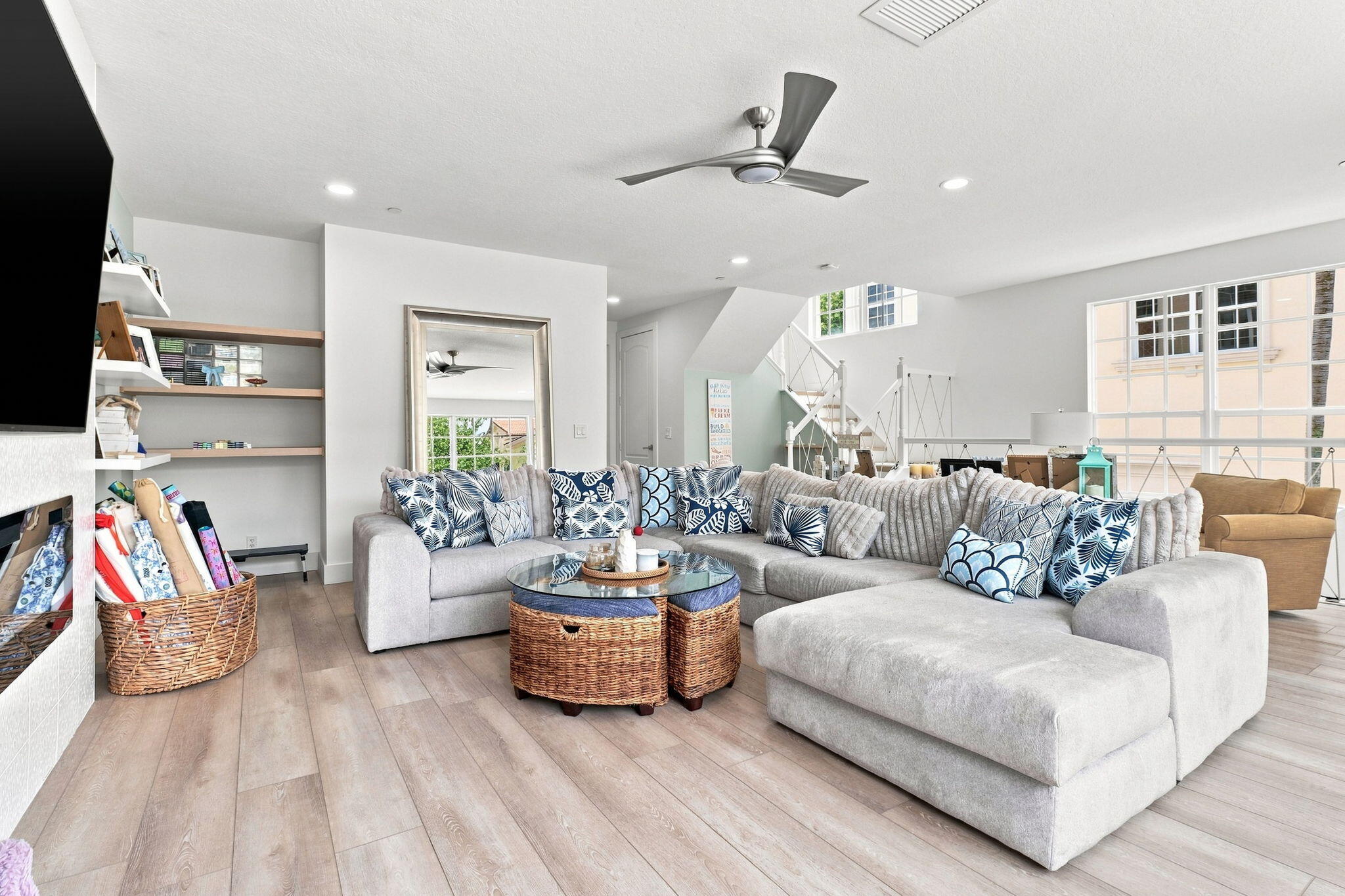 Spacious living area featuring luxury vinyl flooring, recessed lighting, a ceiling fan, built-in shelving and a prominent staircase with nautical railings