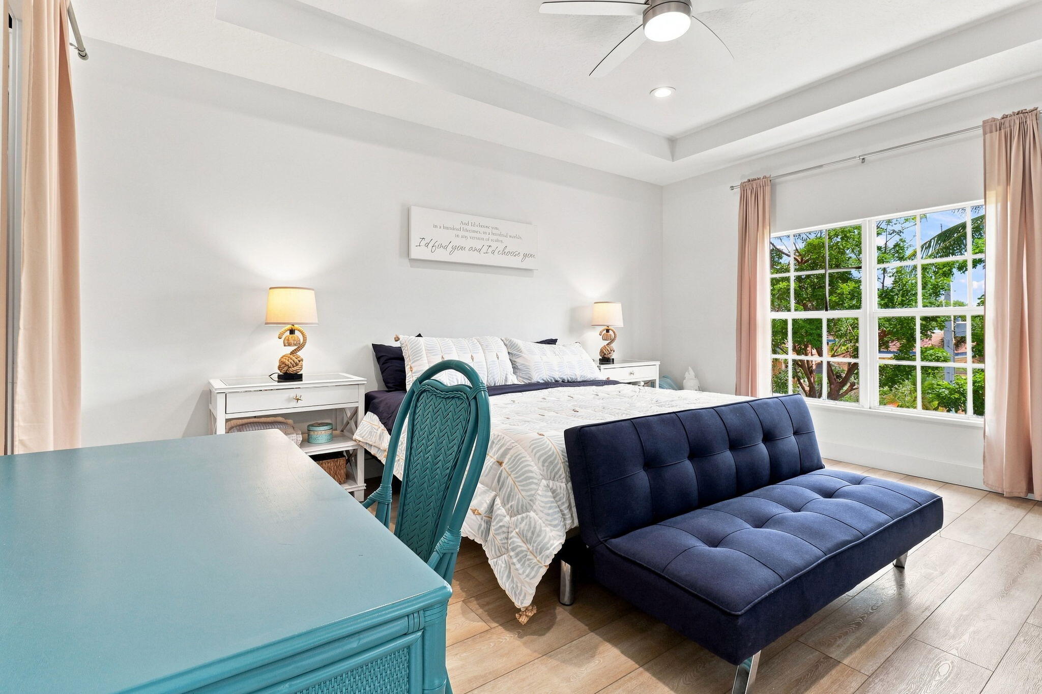 Tray ceiling with a ceiling fan, luxury vinyl flooring and a large window
