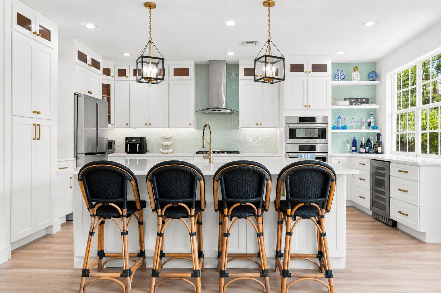 White shaker cabinetry with gold-tone hardware, stainless steel appliances and a central island with a solid surface countertop