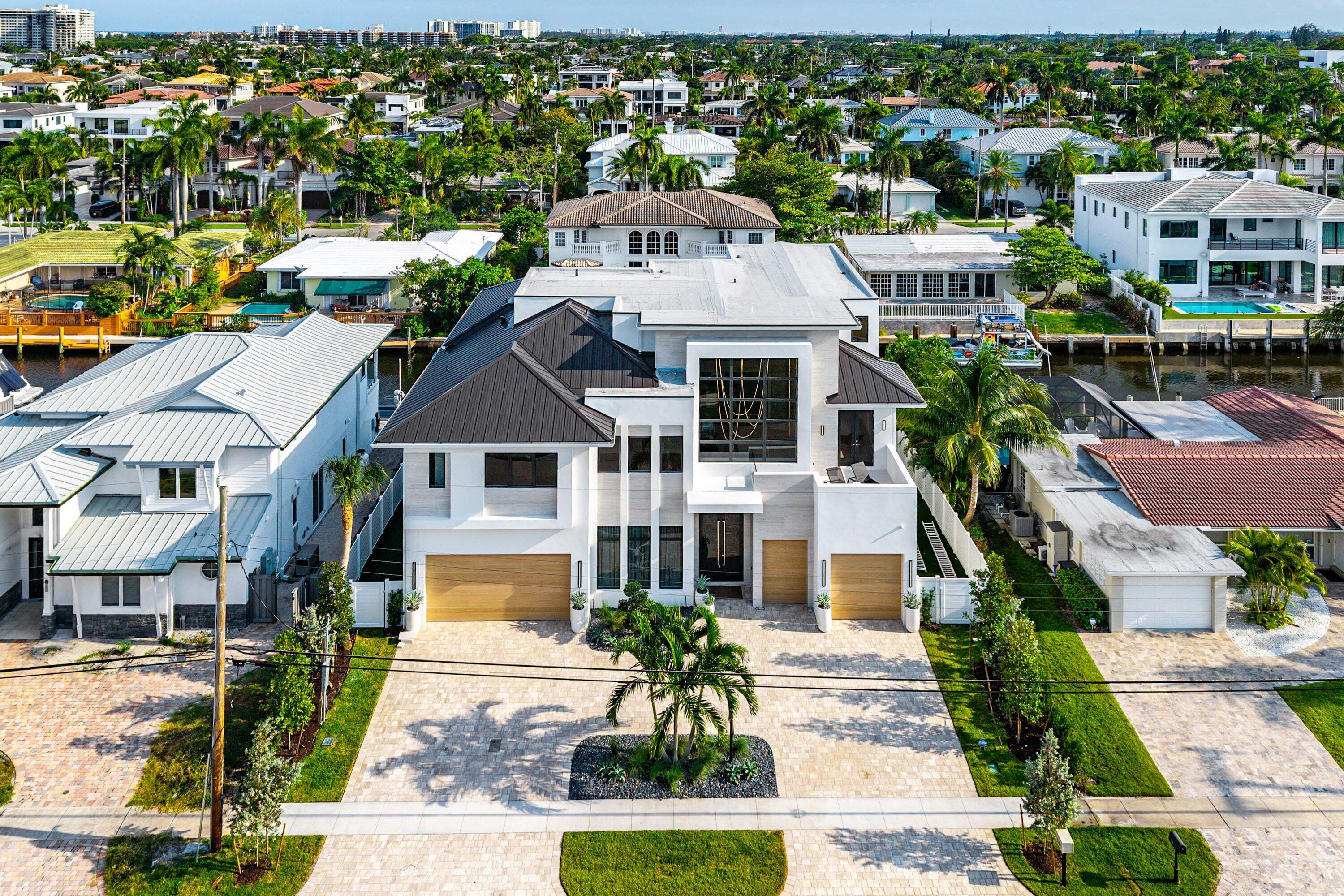 Modern architectural style with a multi-level facade, paver driveway, two wood-finish garage doors, and a prominent entry with a glass-paneled door