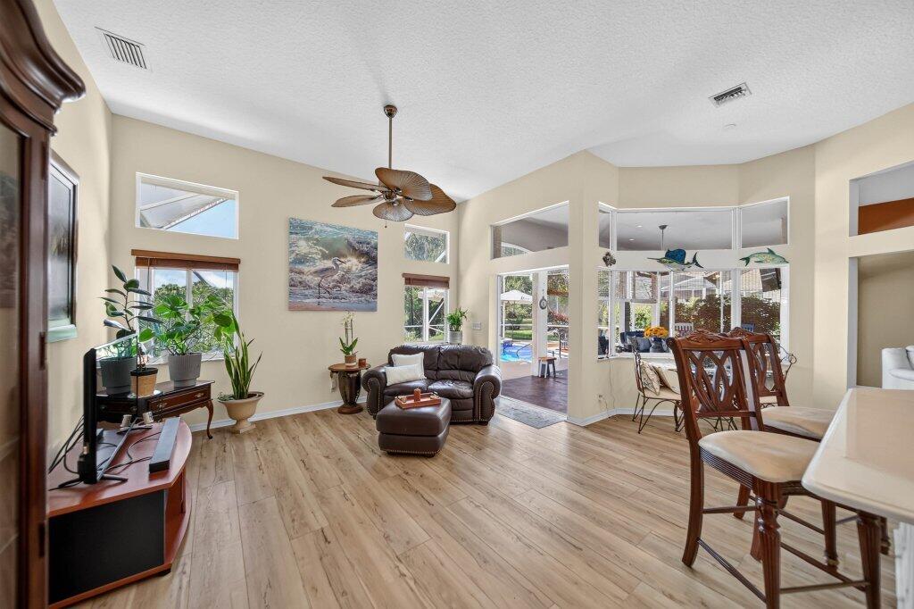 Vaulted ceilings featuring a ceiling fan, wood-finish flooring, and multiple windows