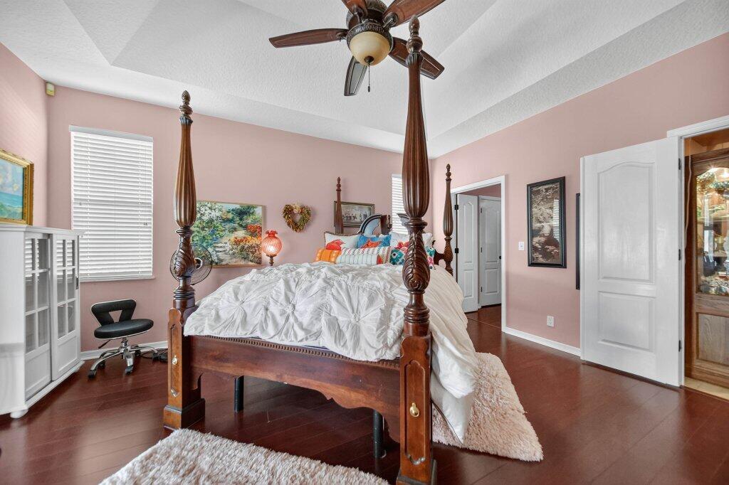 Spacious Main Bedroom. Tray ceiling with a ceiling fan, dark wood-finish flooring, and white interior doors