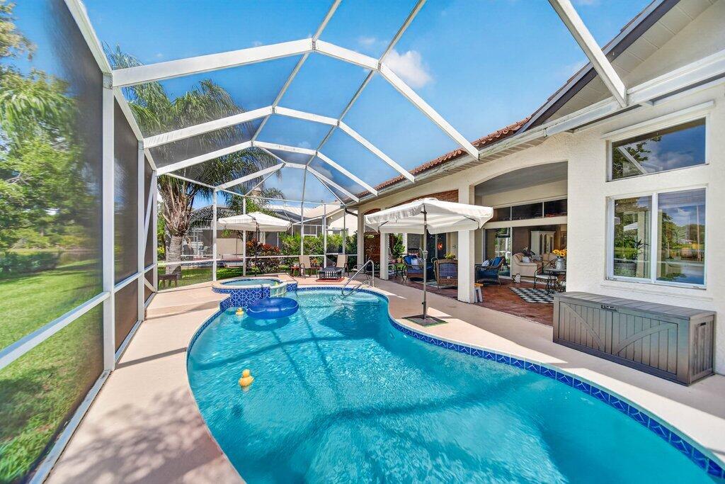 Screened enclosure featuring a freeform pool, integrated spa, and a light-colored concrete deck