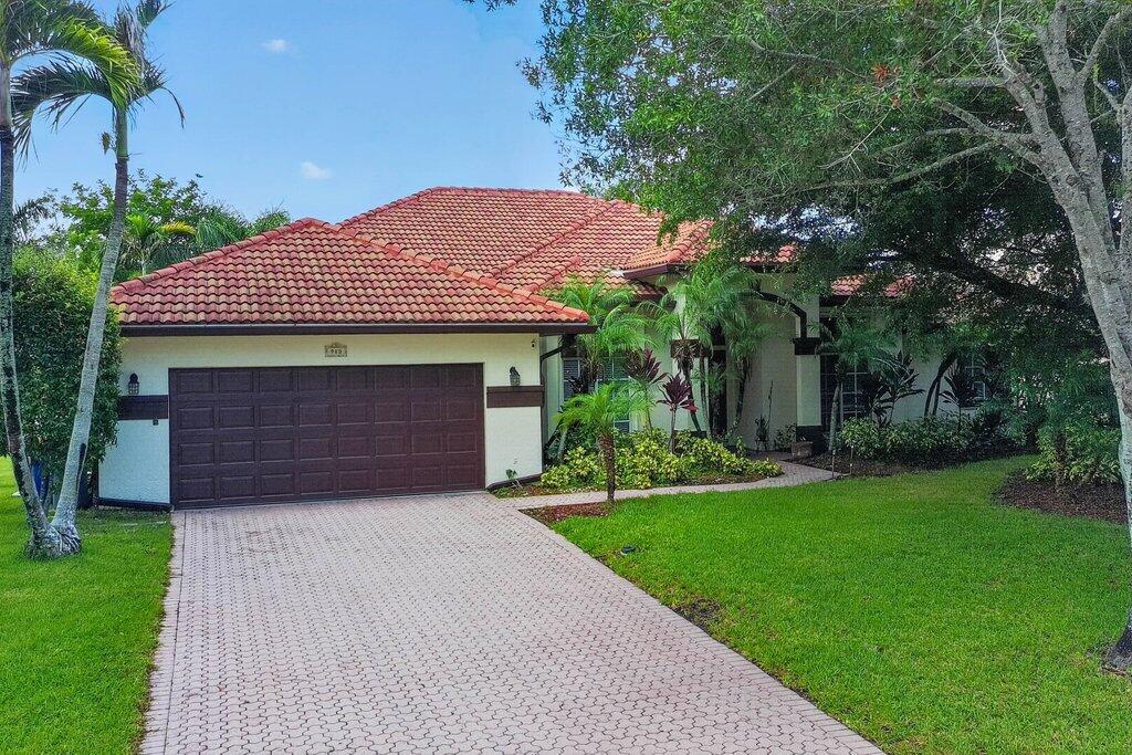 Mediterranean-style residence featuring a tile roof, an integrated two-car garage, and a paver driveway