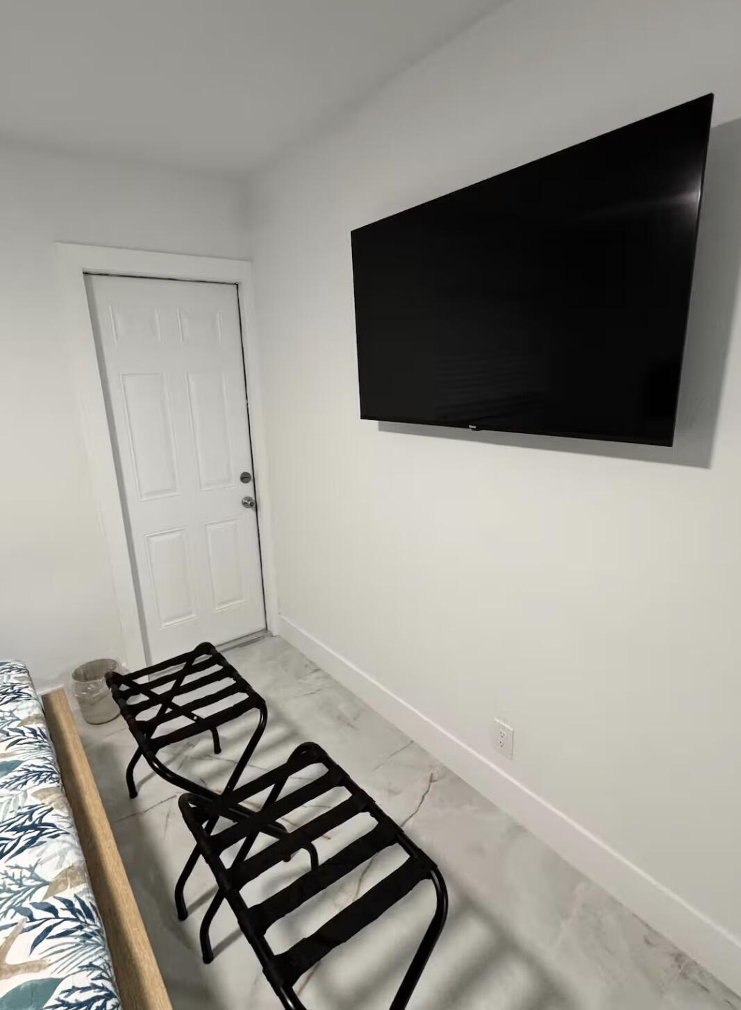Well-appointed bedroom featuring a wall-mounted TV, comfortable seating area, and elegant marble-look tile flooring