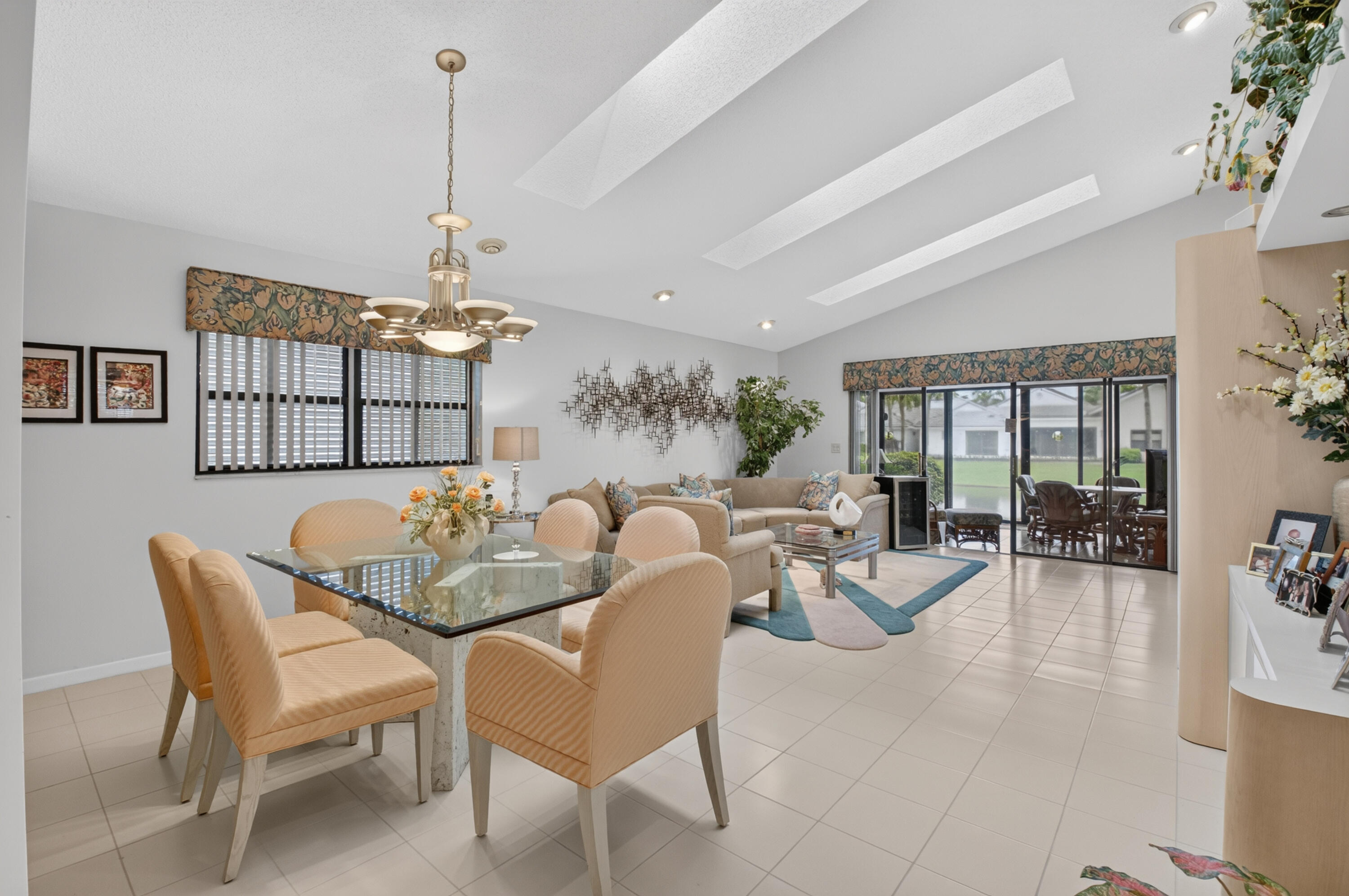 Vaulted ceilings with recessed lighting, large glass slider, ceramic tile flooring, and a dining area chandelier