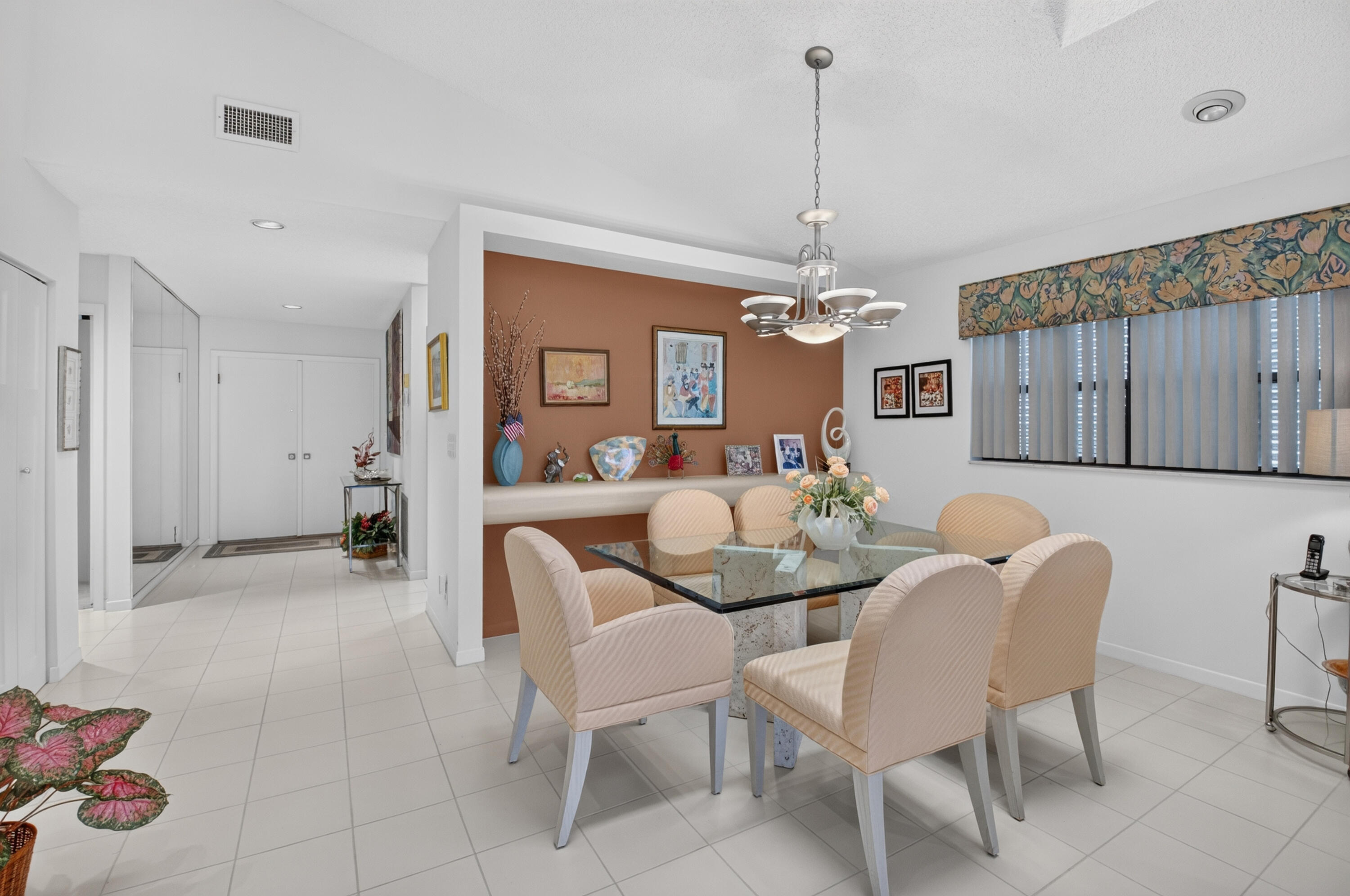 Recessed lighting throughout, tile flooring, built-in shelving, window with vertical blinds, and a chandelier lighting fixture