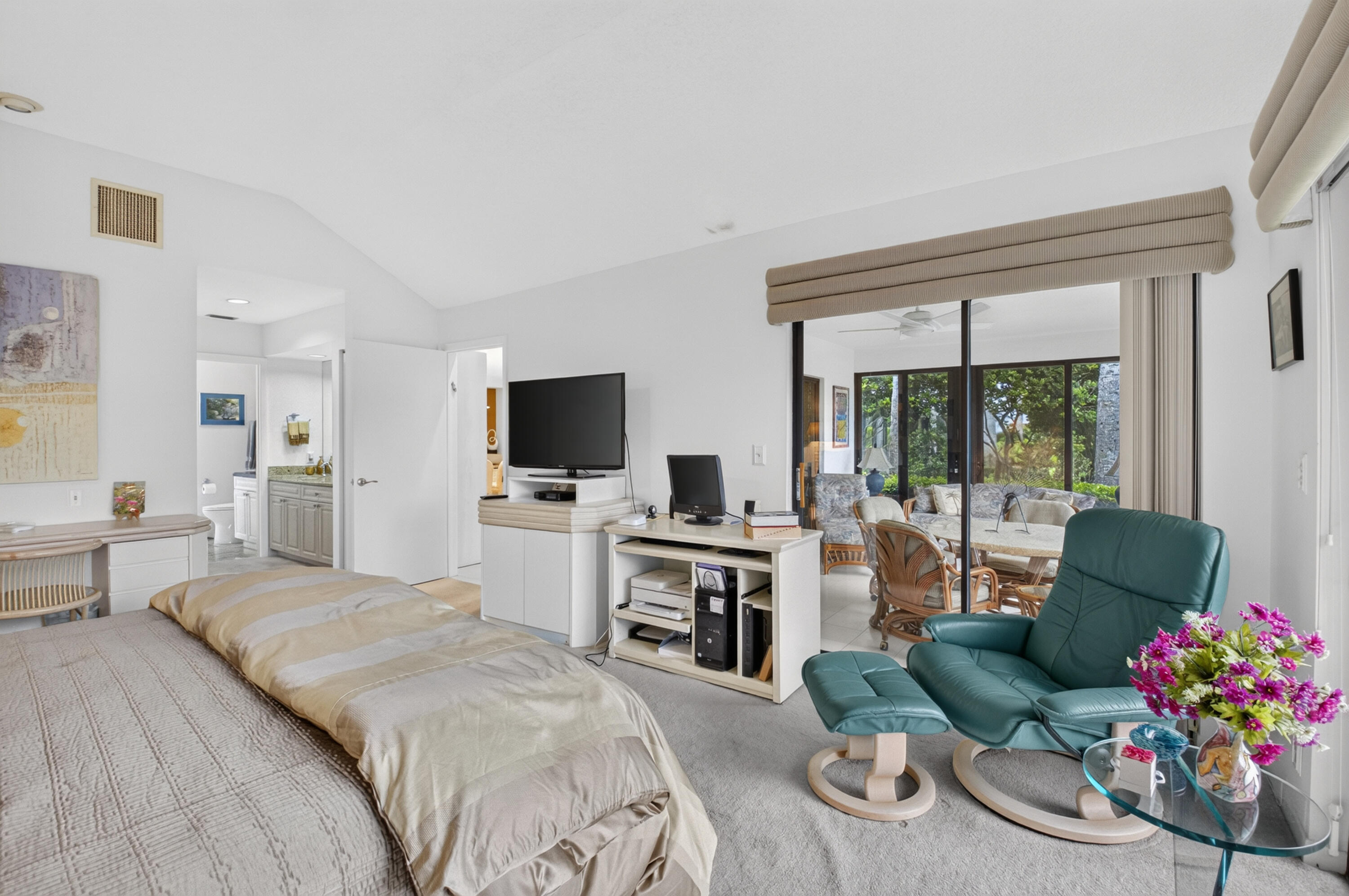 Vaulted ceilings, carpet flooring, sliding glass doors, and a bathroom with a vanity