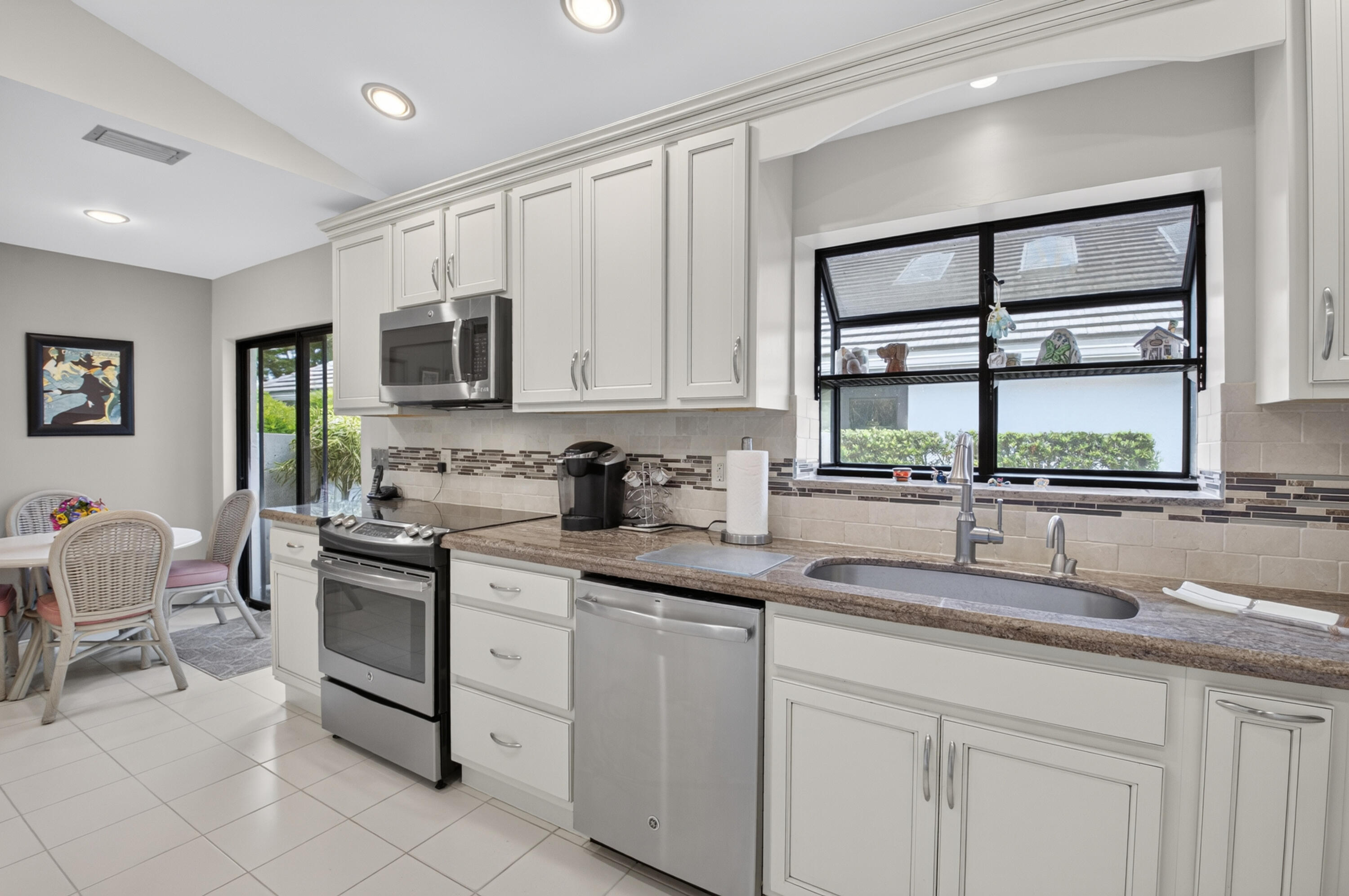 Kitchen featuring white cabinetry, stainless steel appliances, a tiled backsplash, a built-in sink, and recessed lighting