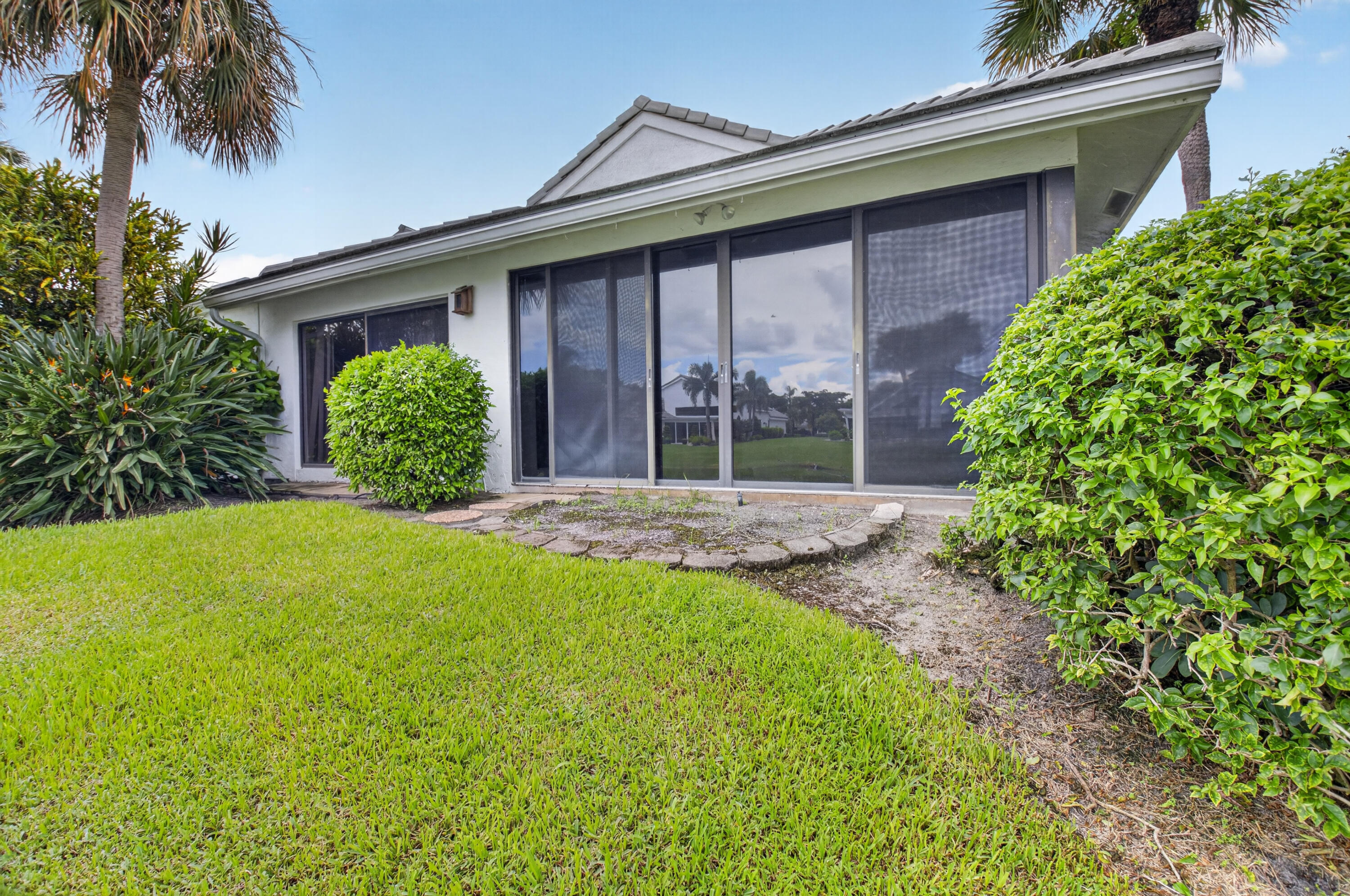 Expansive rear lawn, mature landscaping, and multi-panel sliding glass doors
