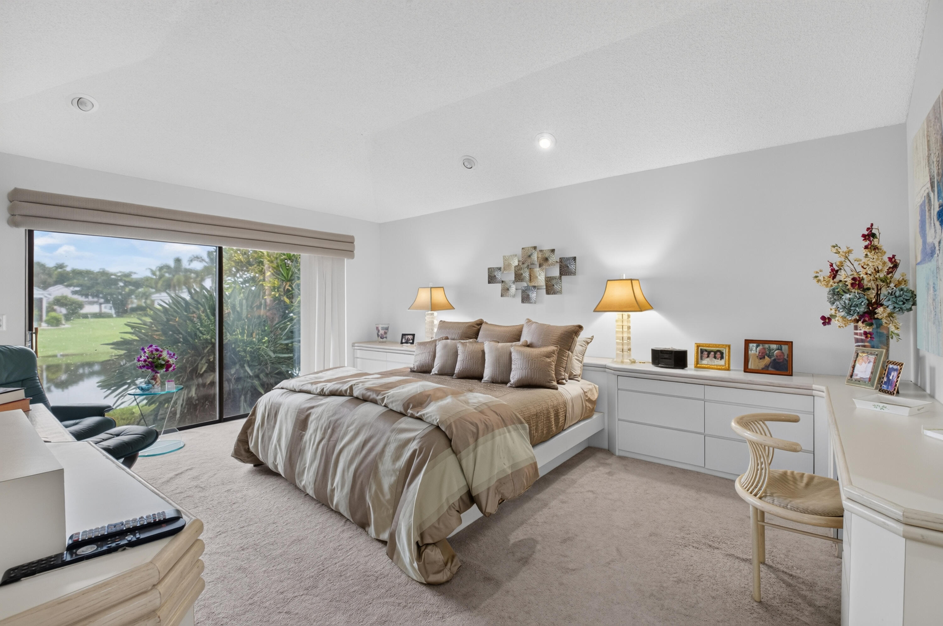 Expansive sliding glass doors, built-in recessed lighting, and soft carpeting