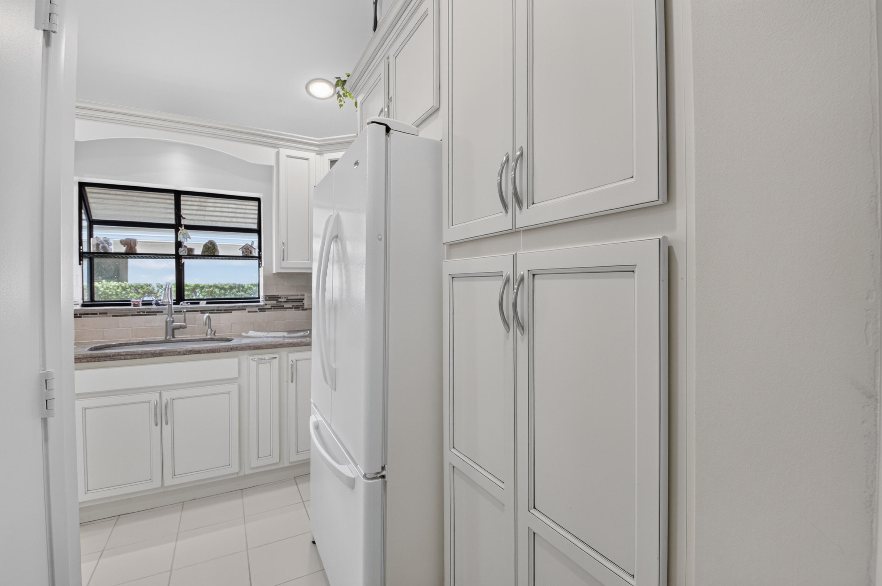 White shaker-style cabinetry, tile flooring, built-in storage, and a stainless steel sink with a single-handle faucet