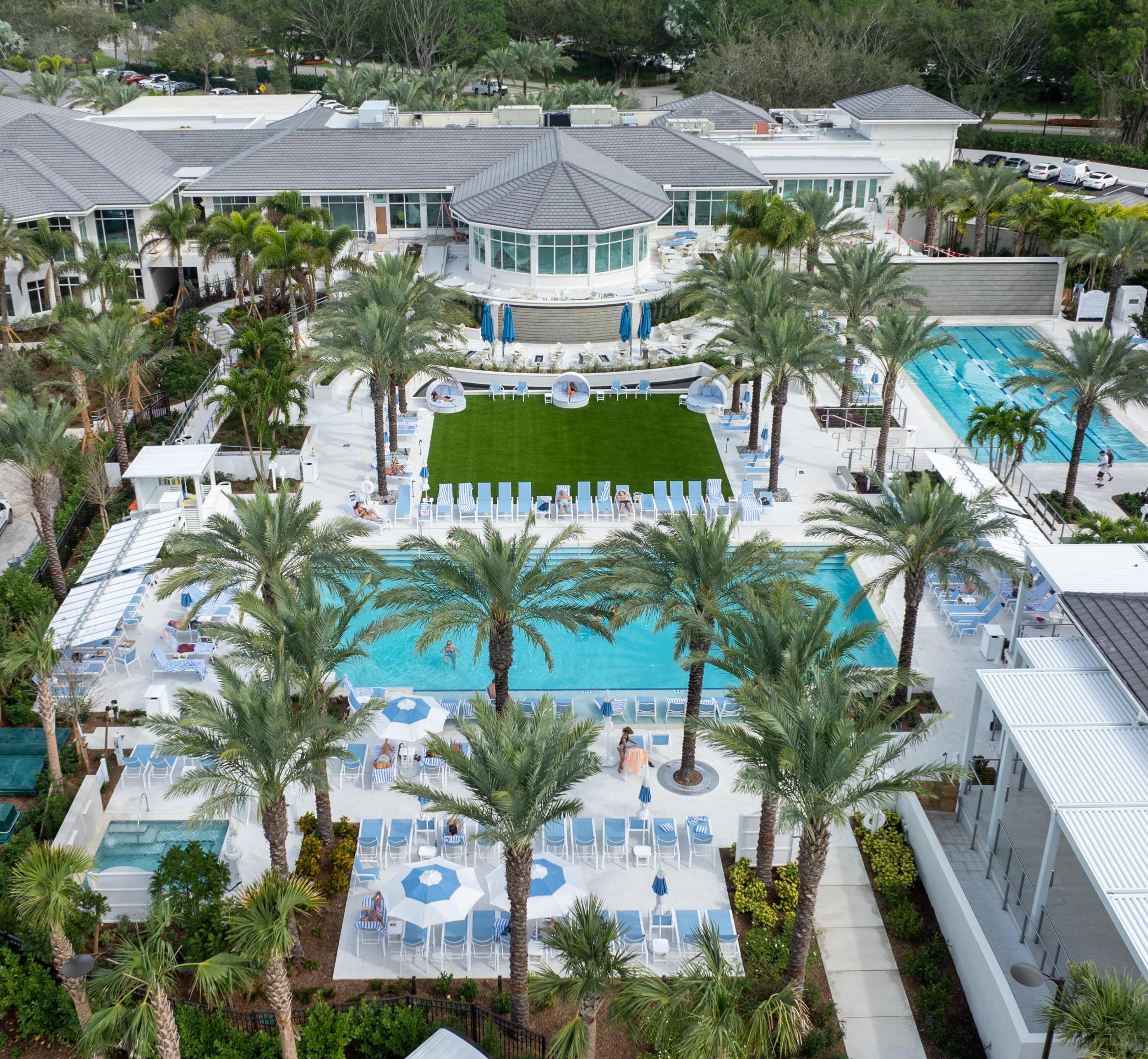 Resort-style amenities featuring multiple swimming pools, a lap pool, a spa, an expansive turf lawn, and extensive tropical landscaping