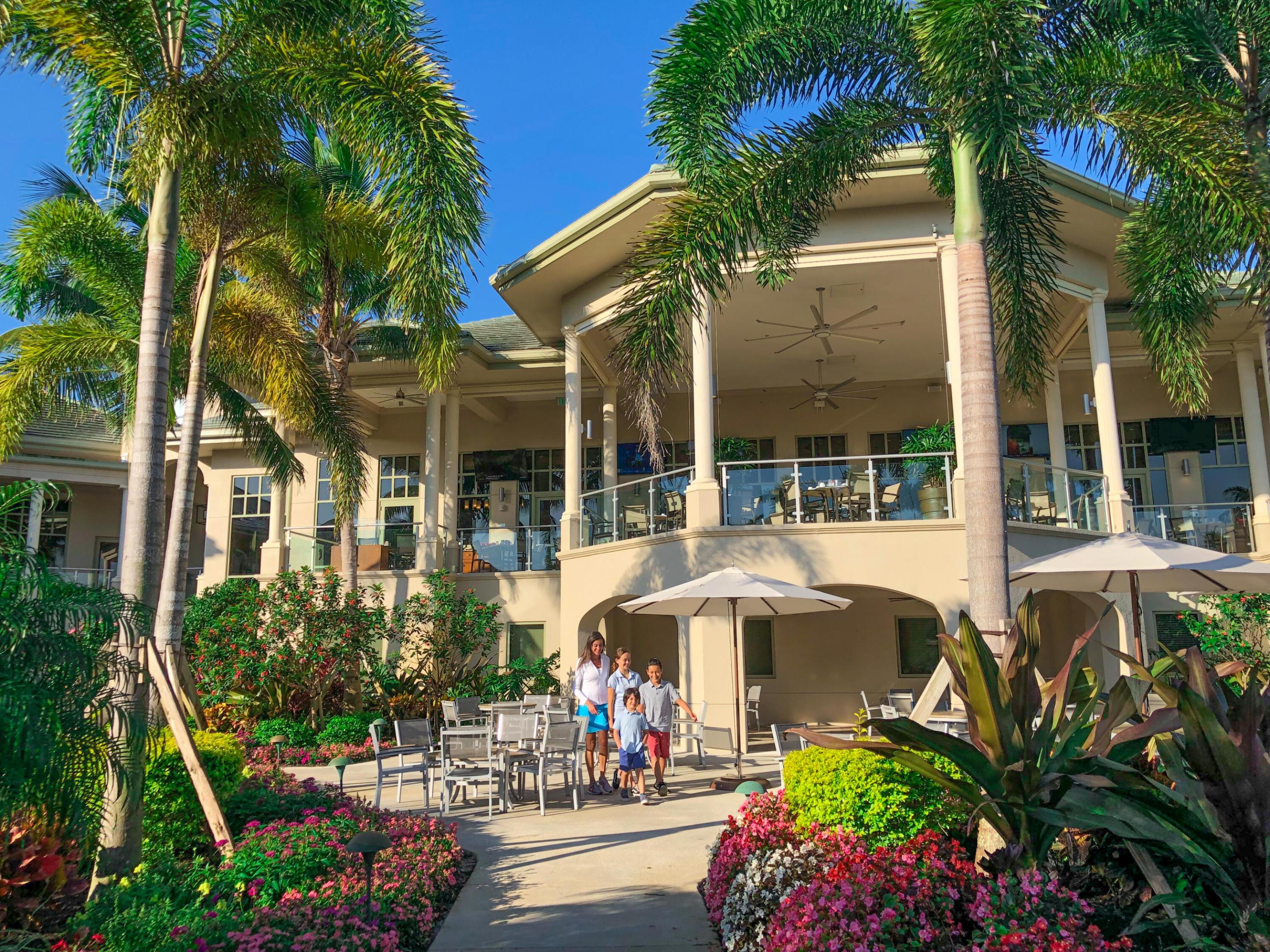 Two-story stucco exterior with a covered balcony, clear glass railings, and multiple ceiling fans