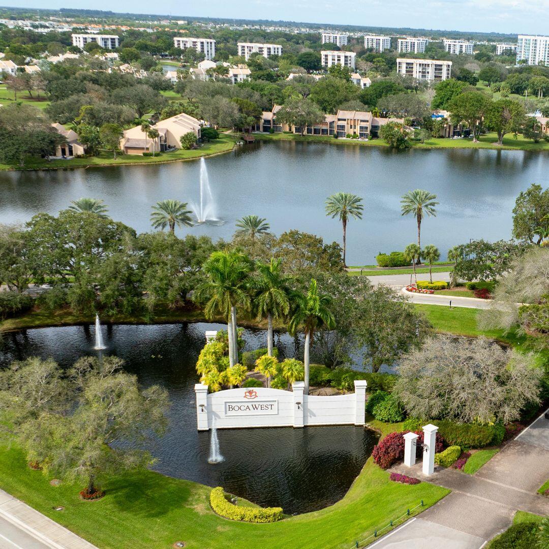 Aerial perspective showcasing a community entrance with a decorative sign, surrounded by a body of water with water features