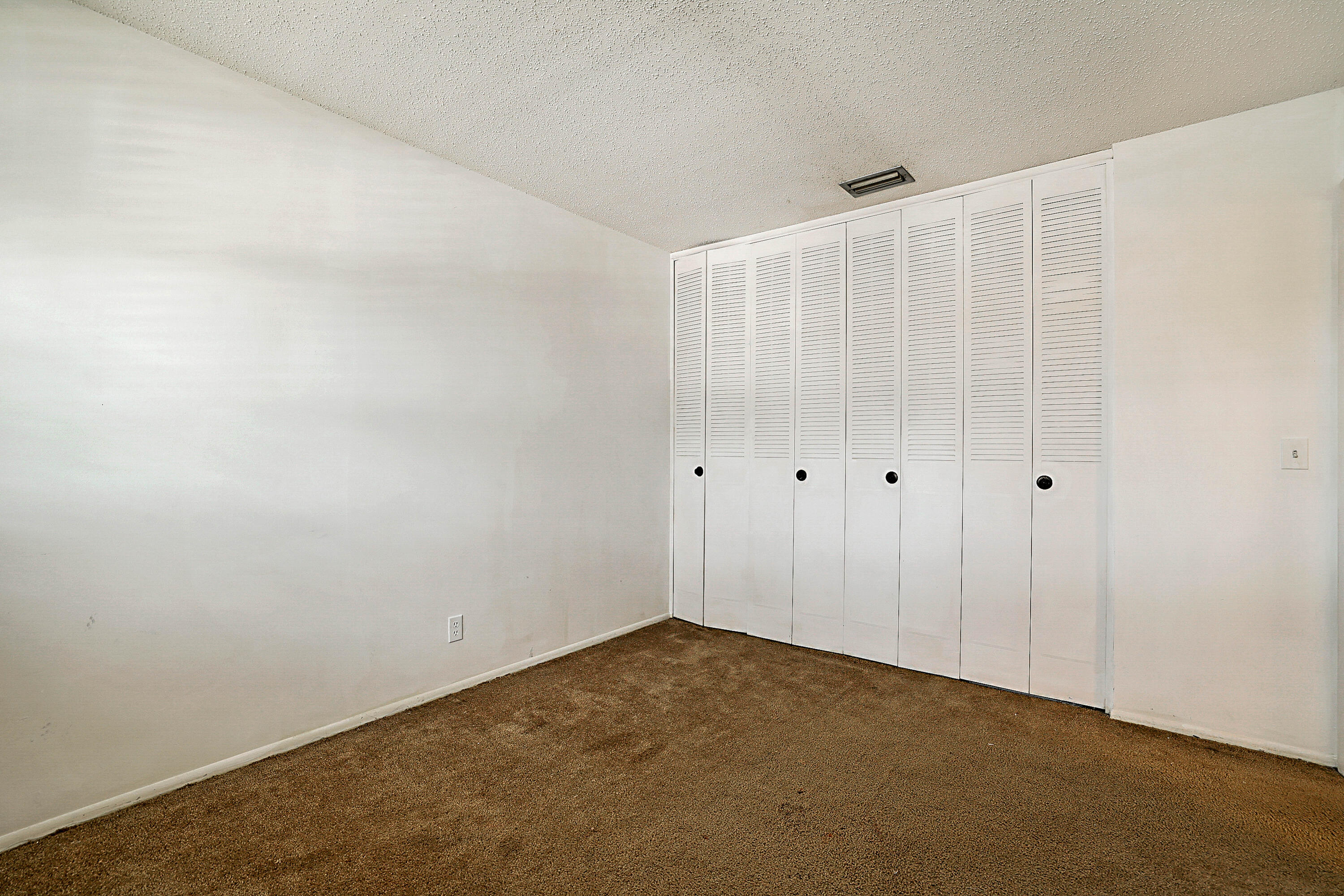 White walls with textured ceiling and brown carpet