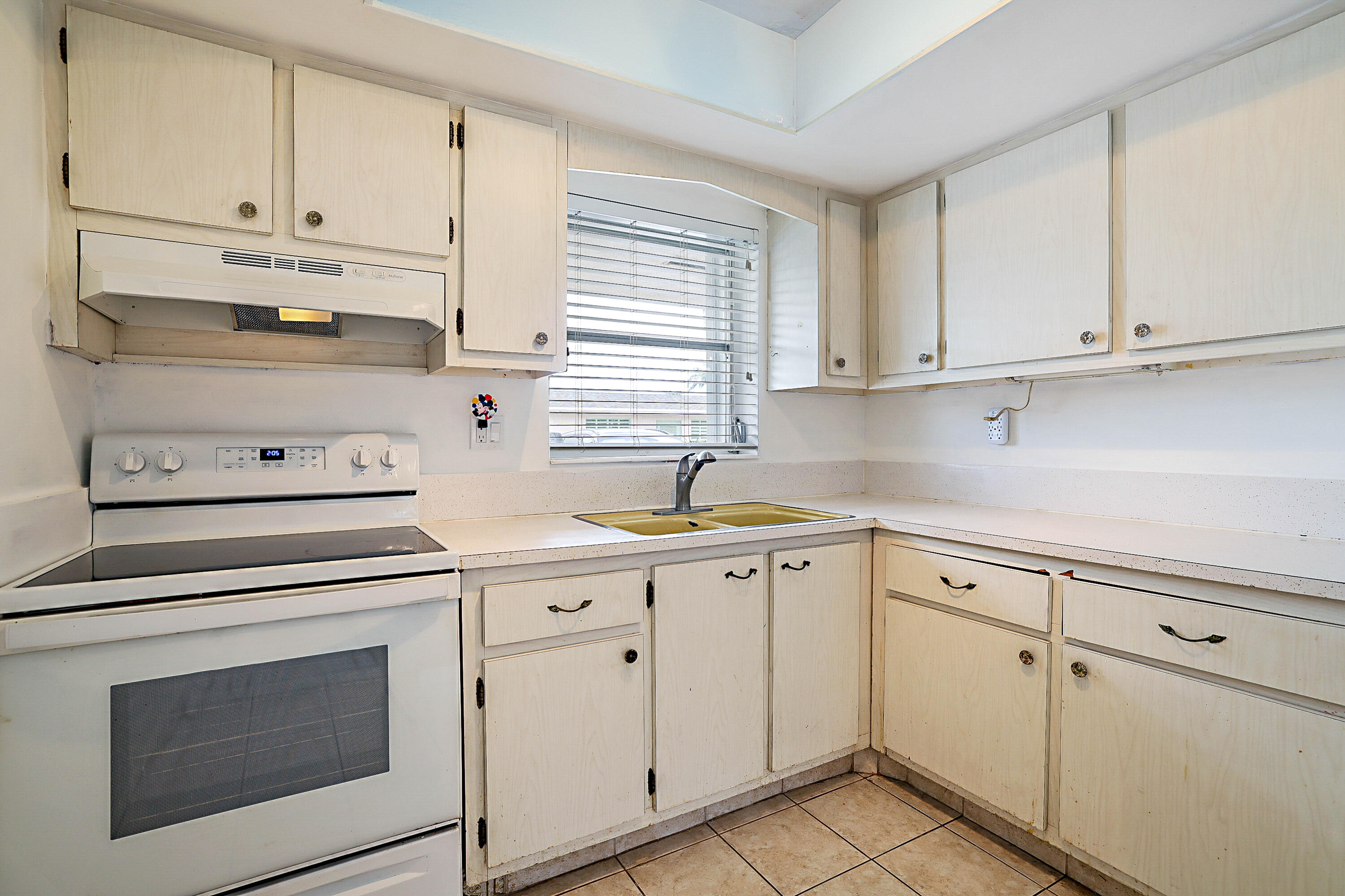 Kitchen with white cabinetry, a built-in range, a double basin sink, and tiled flooring