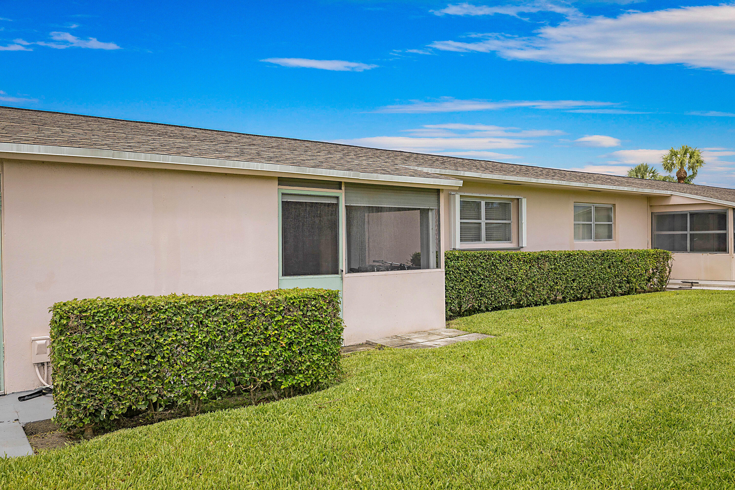Manicured lawn with mature shrubbery and a screened patio