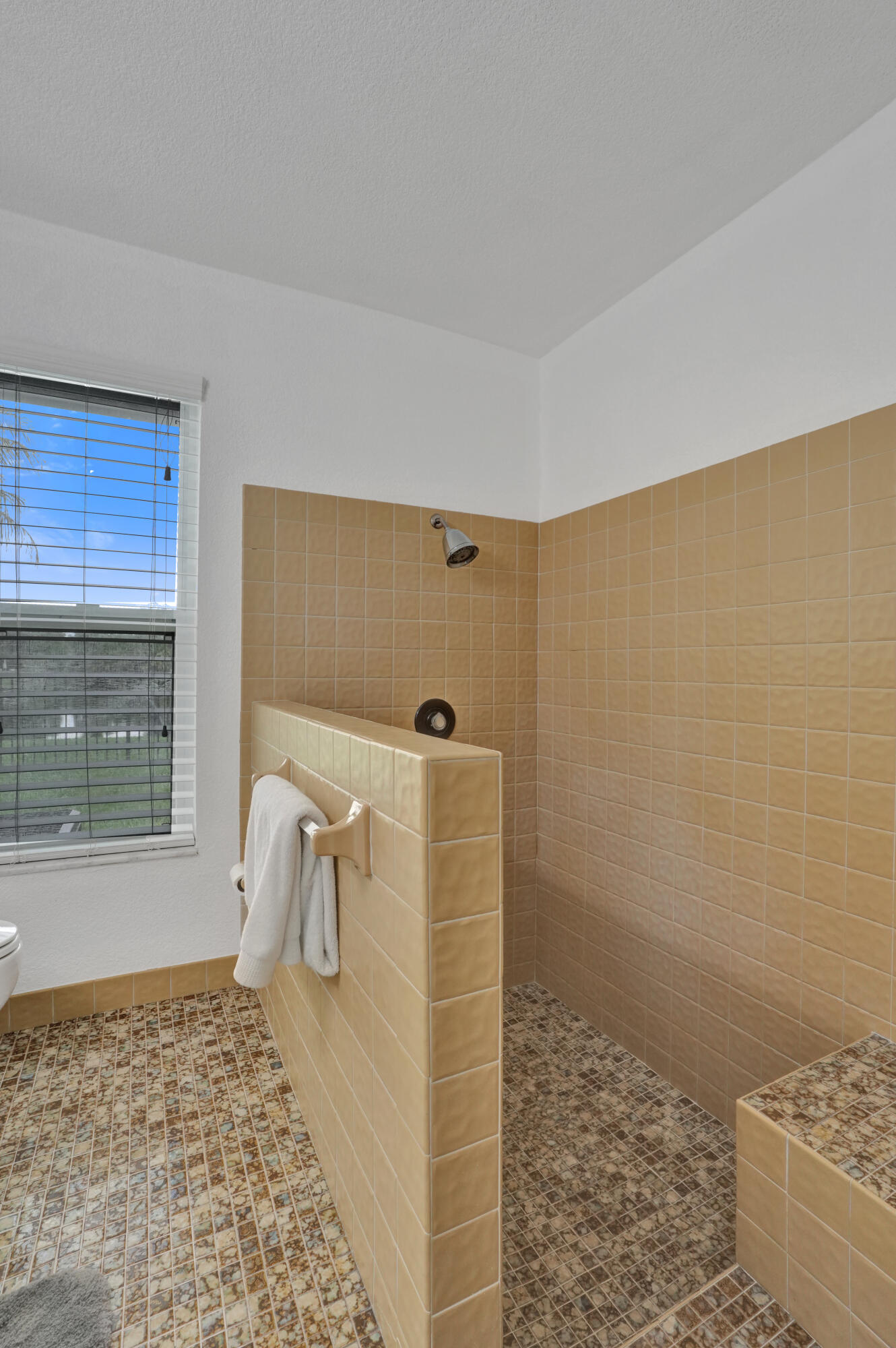 Walk-in shower with full height tile walls, tiled shower floor, and a built-in tiled bench