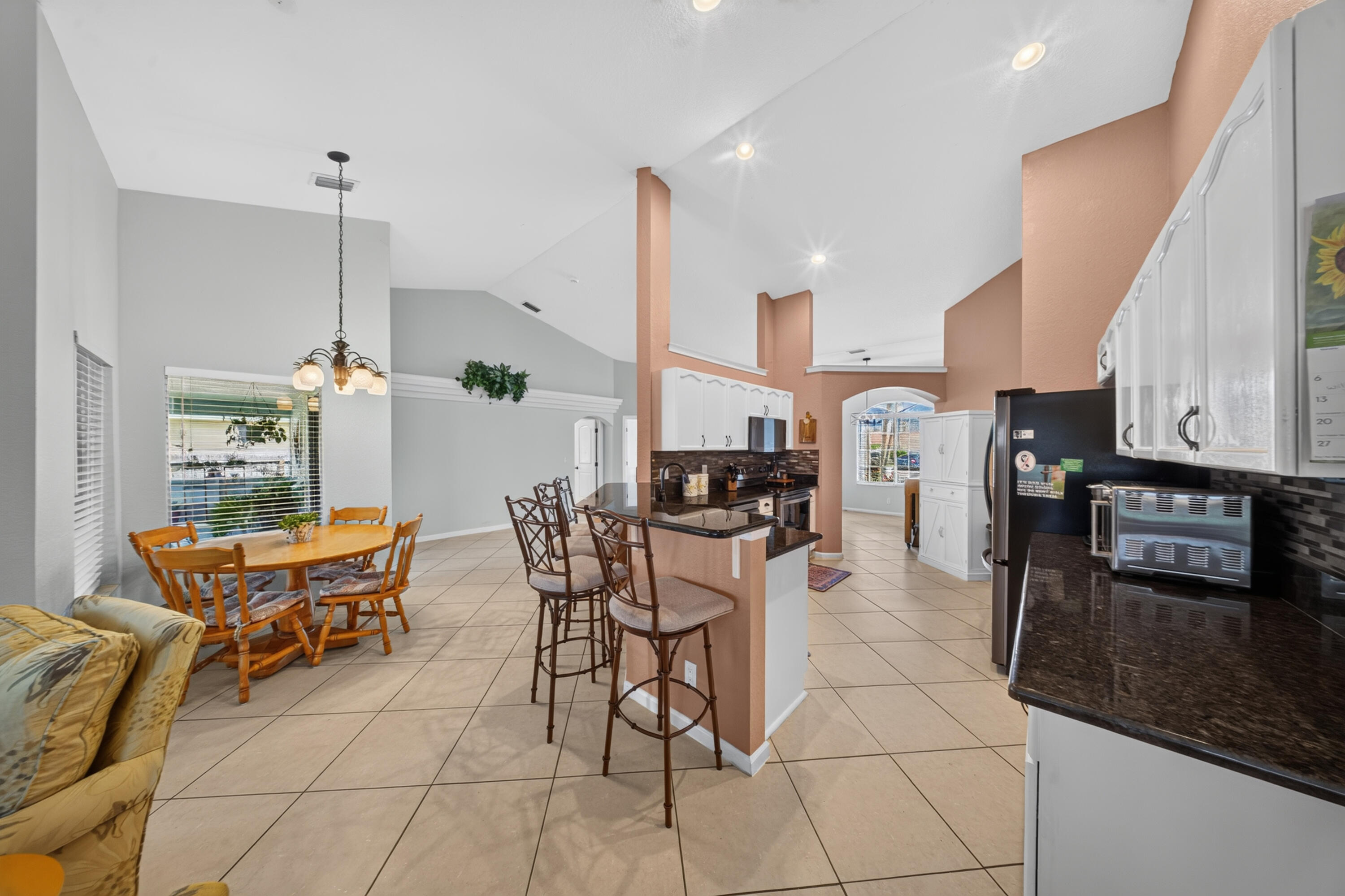 Vaulted ceilings complement the tile flooring throughout this kitchen and dining area