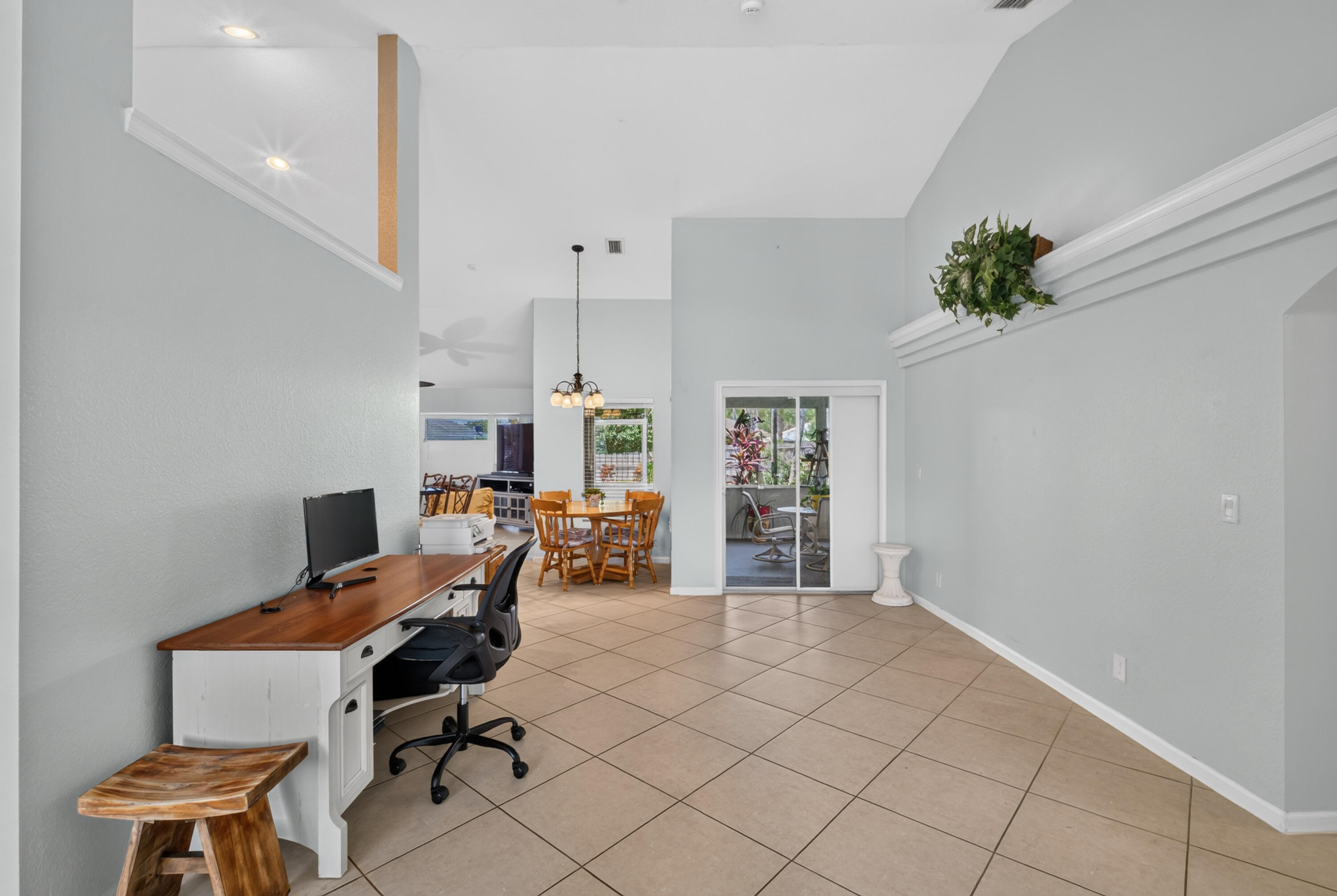 Vaulted ceilings with architectural ledge, tile flooring, and sliding glass door access