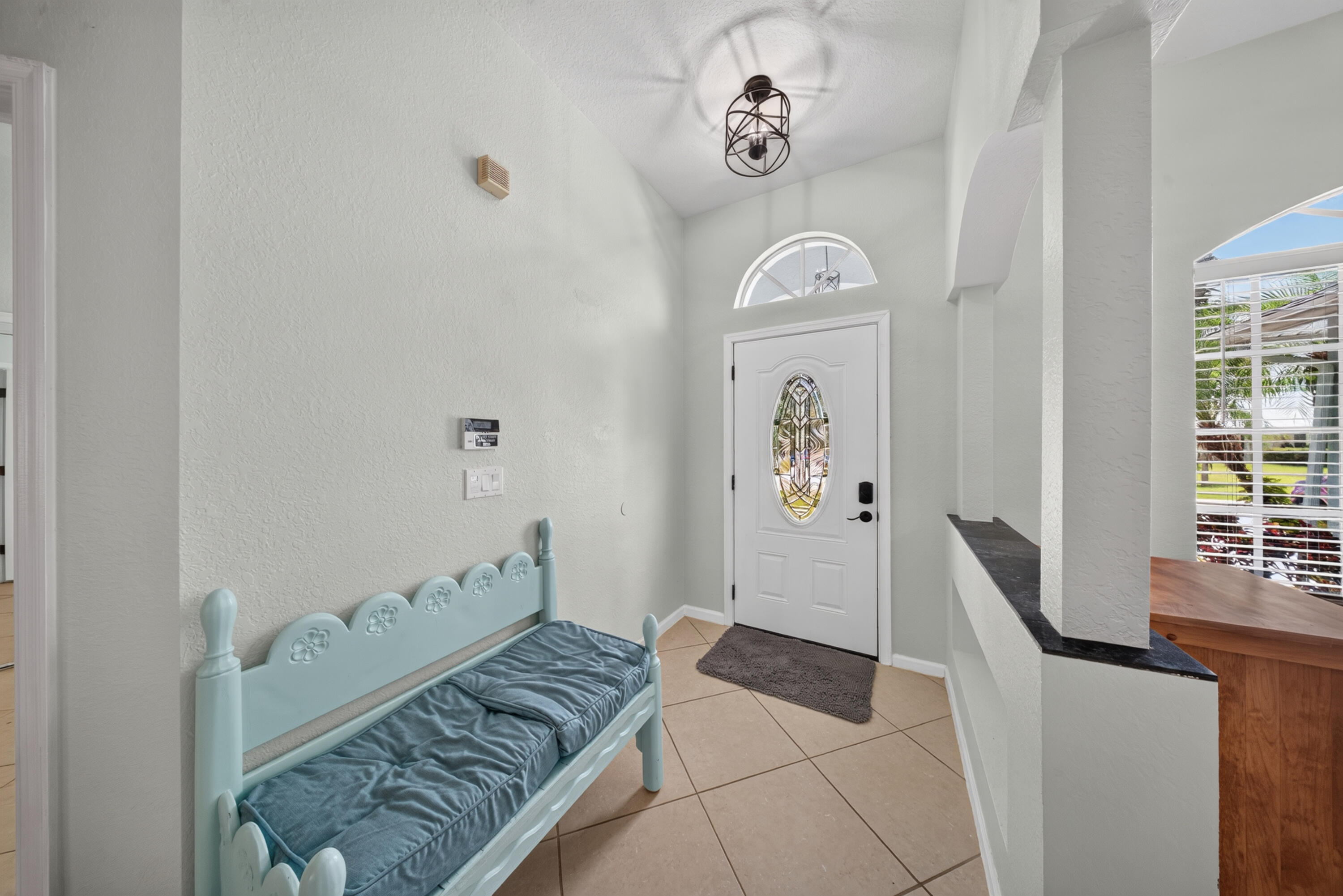 Entryway featuring tile flooring, a decorative front door with an arched transom, a semi-flush mount light fixture, and arched interior openings