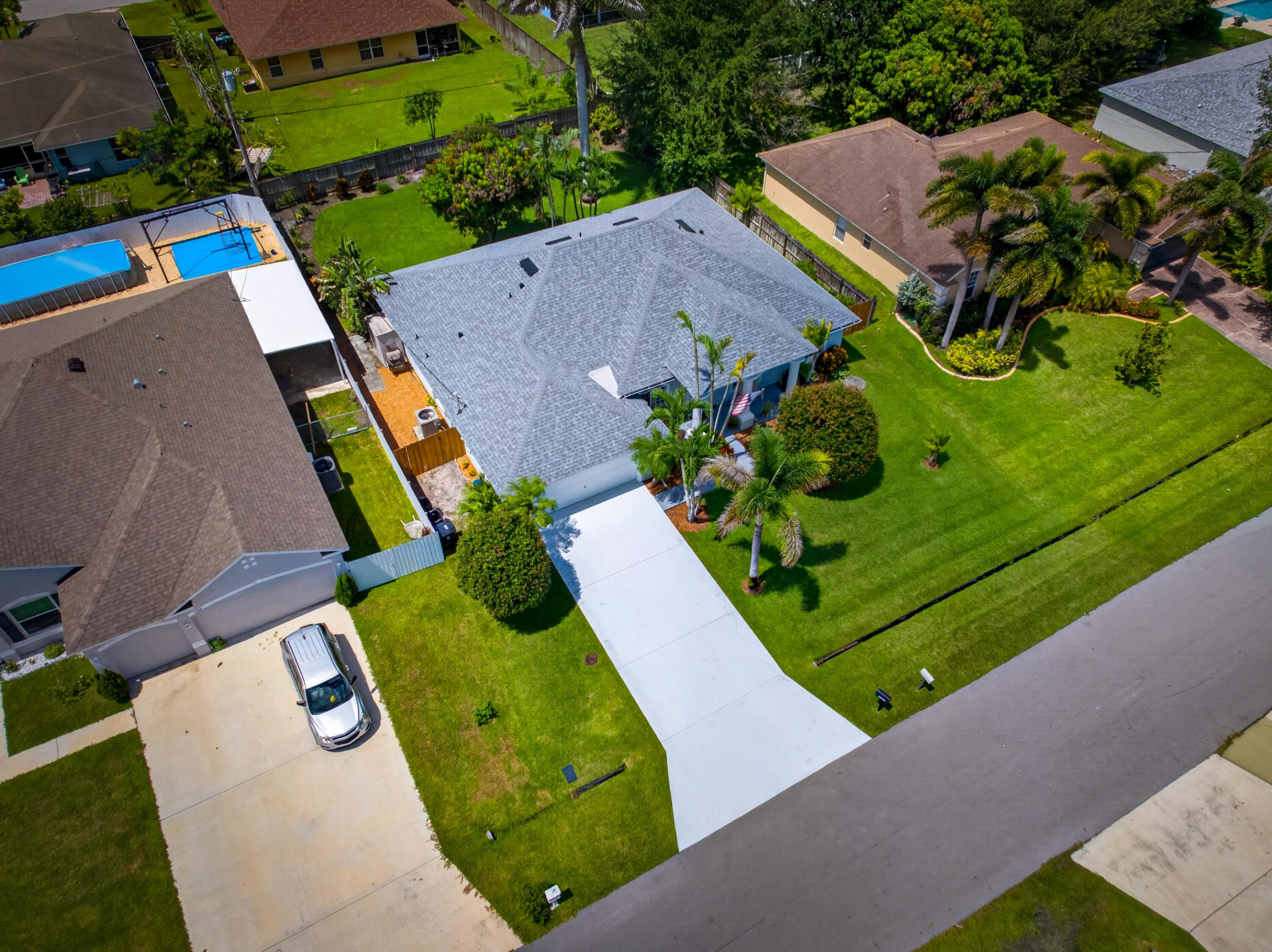 Single-story residence featuring a shingle roof, expansive front lawn with mature landscaping, and a concrete driveway