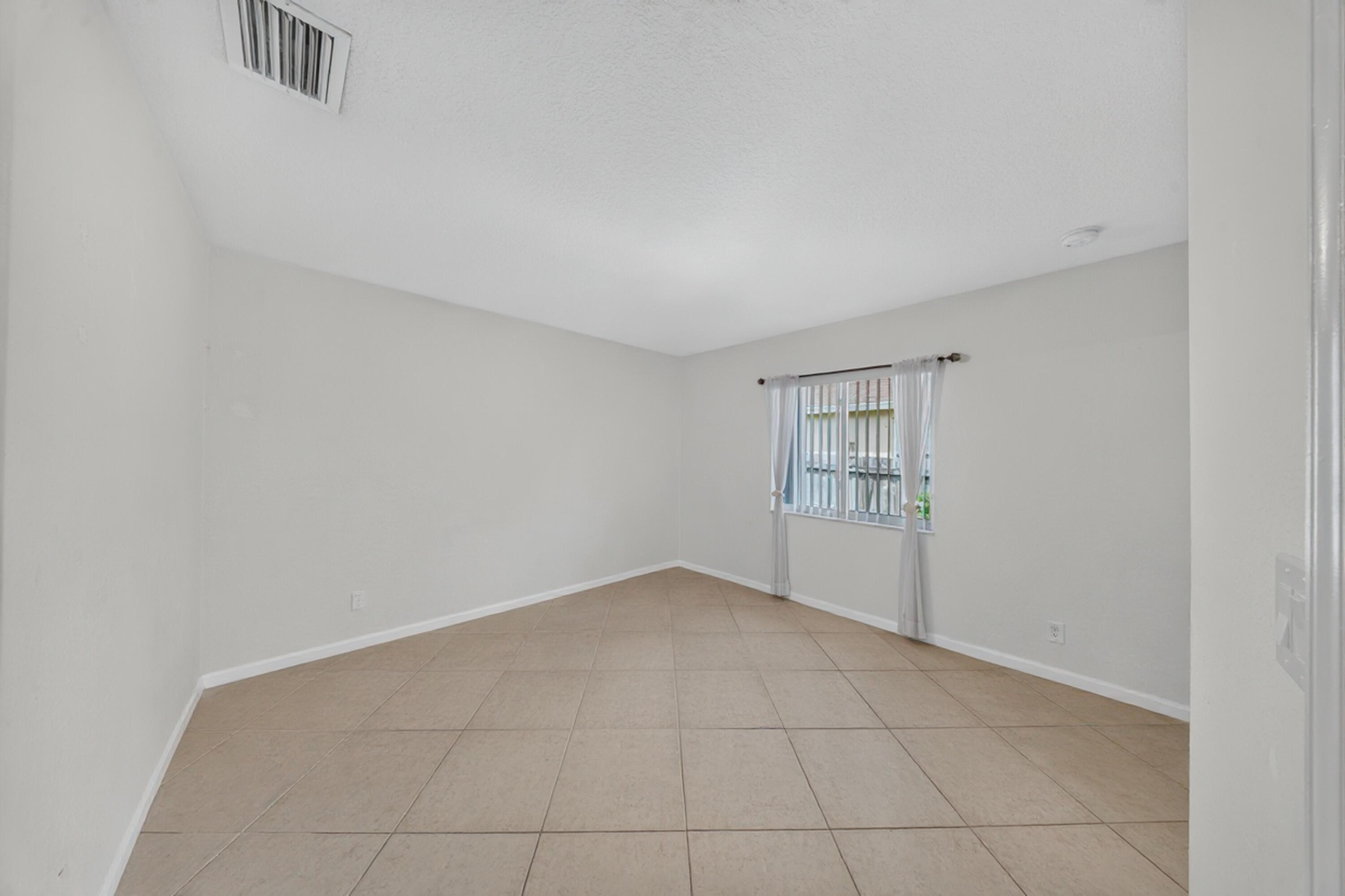 Neutral wall color, tiled flooring, window with security bars, ceiling-mounted ventilation