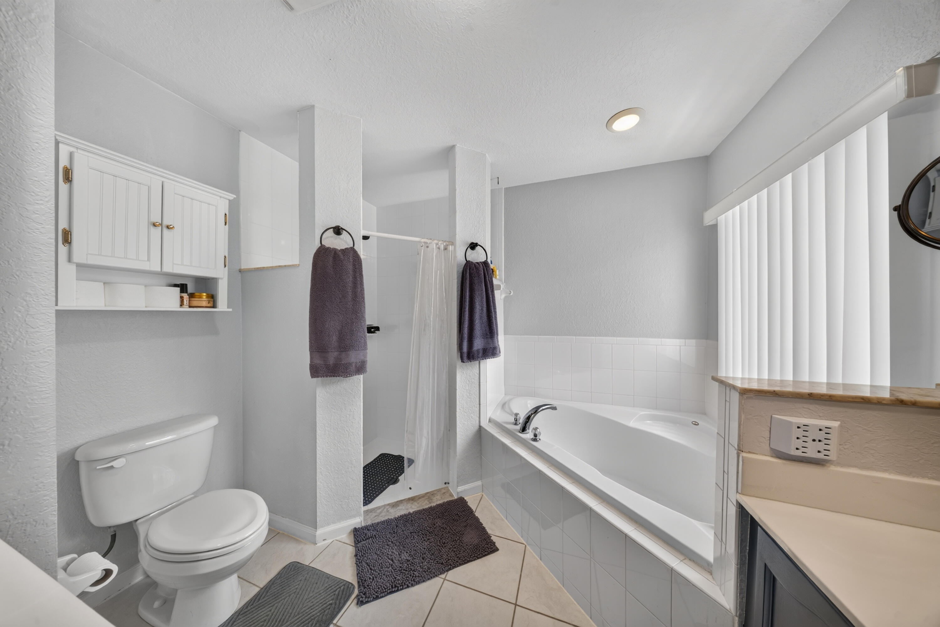 Built-in soaking tub, walk-in shower, wall-mounted storage cabinet, and tiled flooring