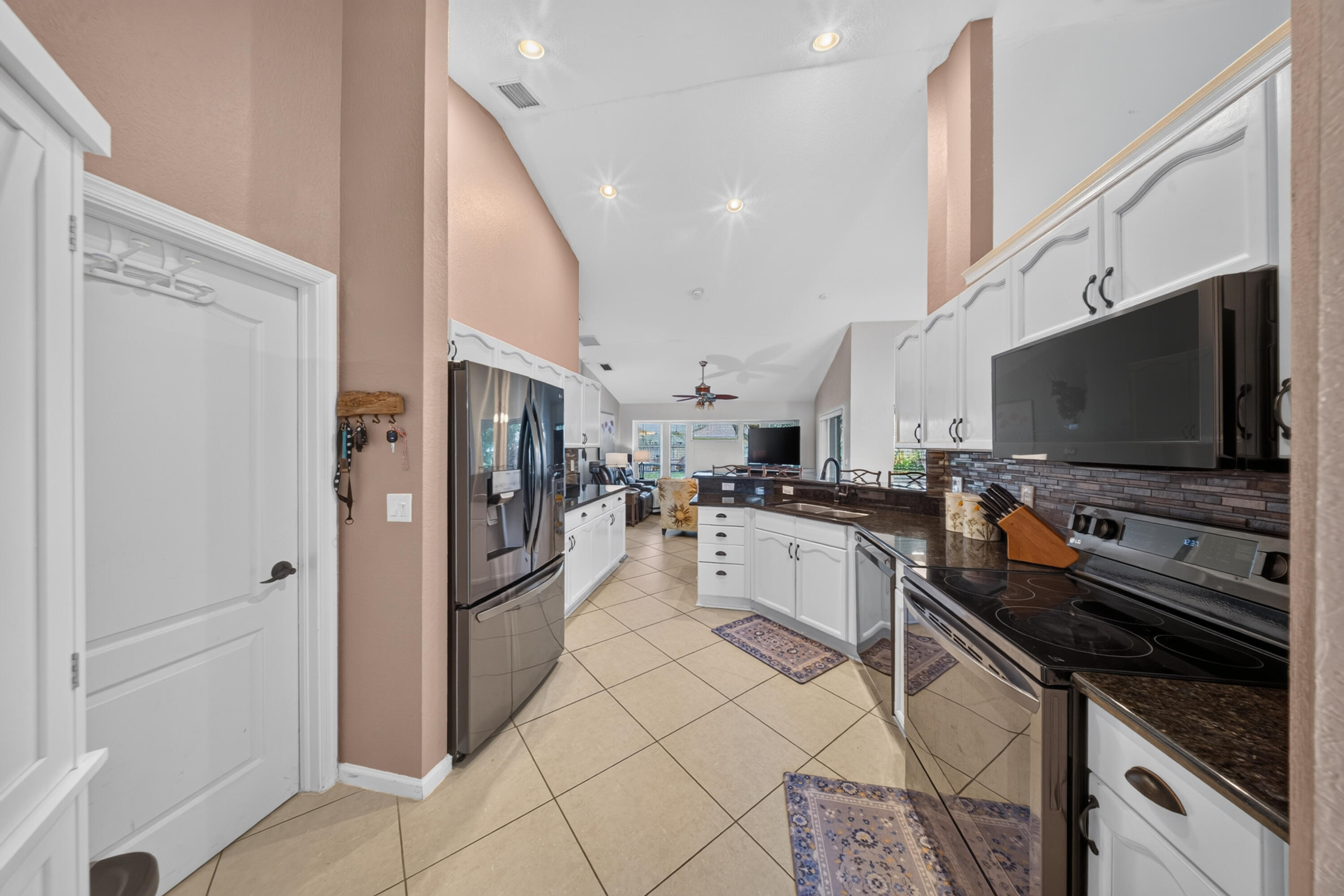 Kitchen featuring white cabinetry, dark countertops, a tile backsplash, stainless steel appliances, and tile flooring