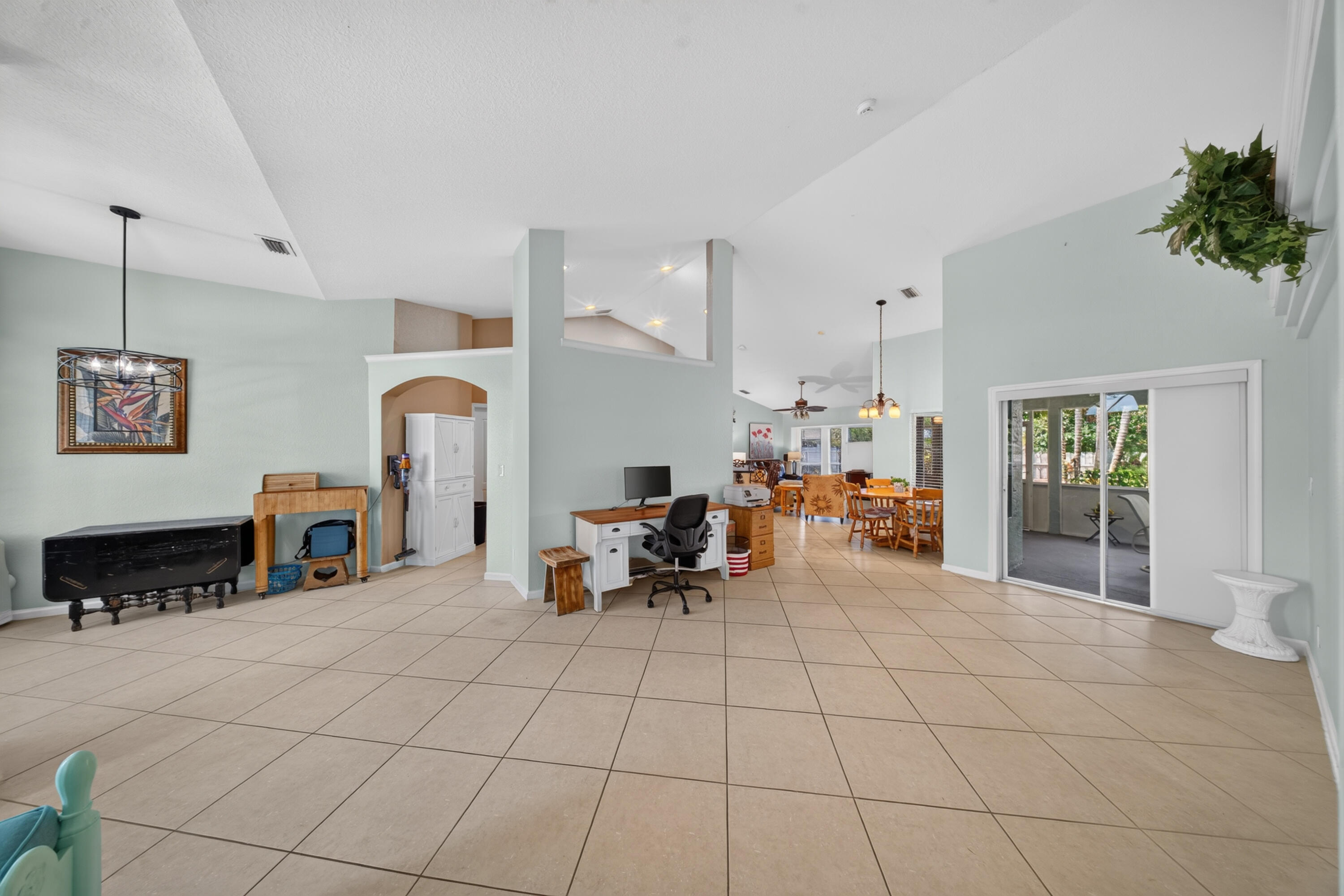 Vaulted ceiling, tiled flooring, arched doorway, sliding glass door, pendant lighting
