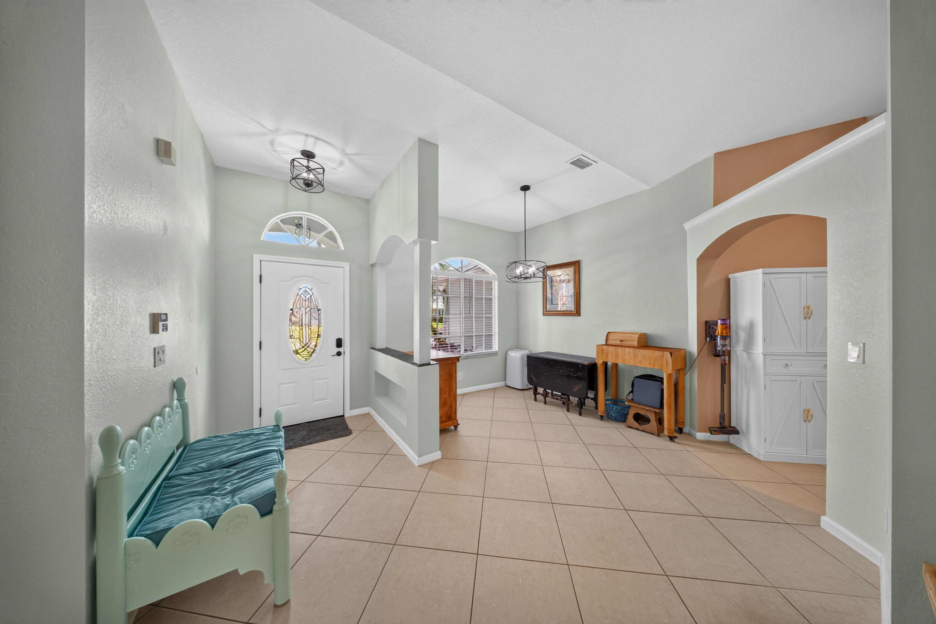 Entryway featuring a white door with decorative glass, arched transom window, and a ceiling-mounted light fixture
