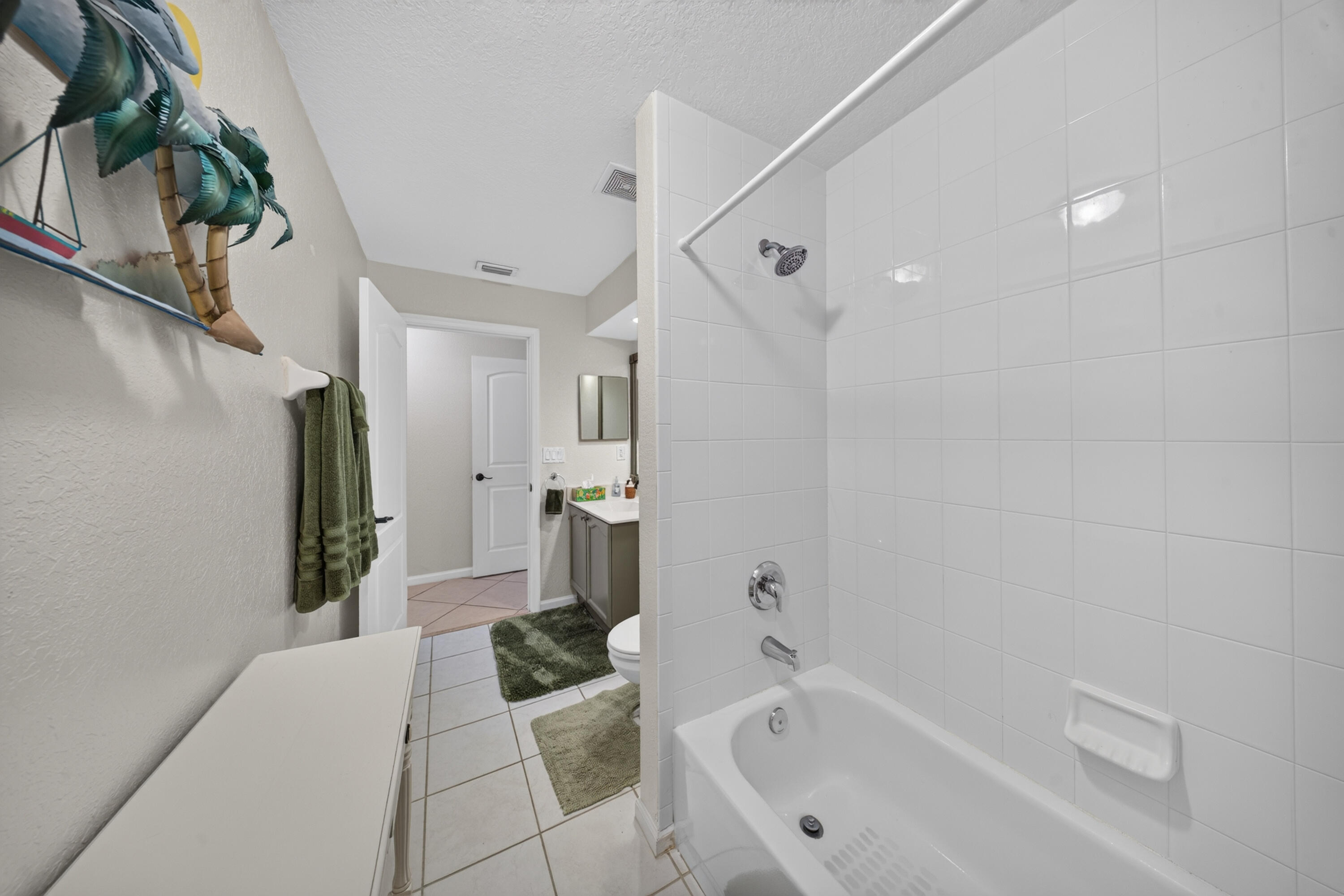Bathroom featuring a white tiled shower with a bathtub, chrome fixtures, and tile flooring